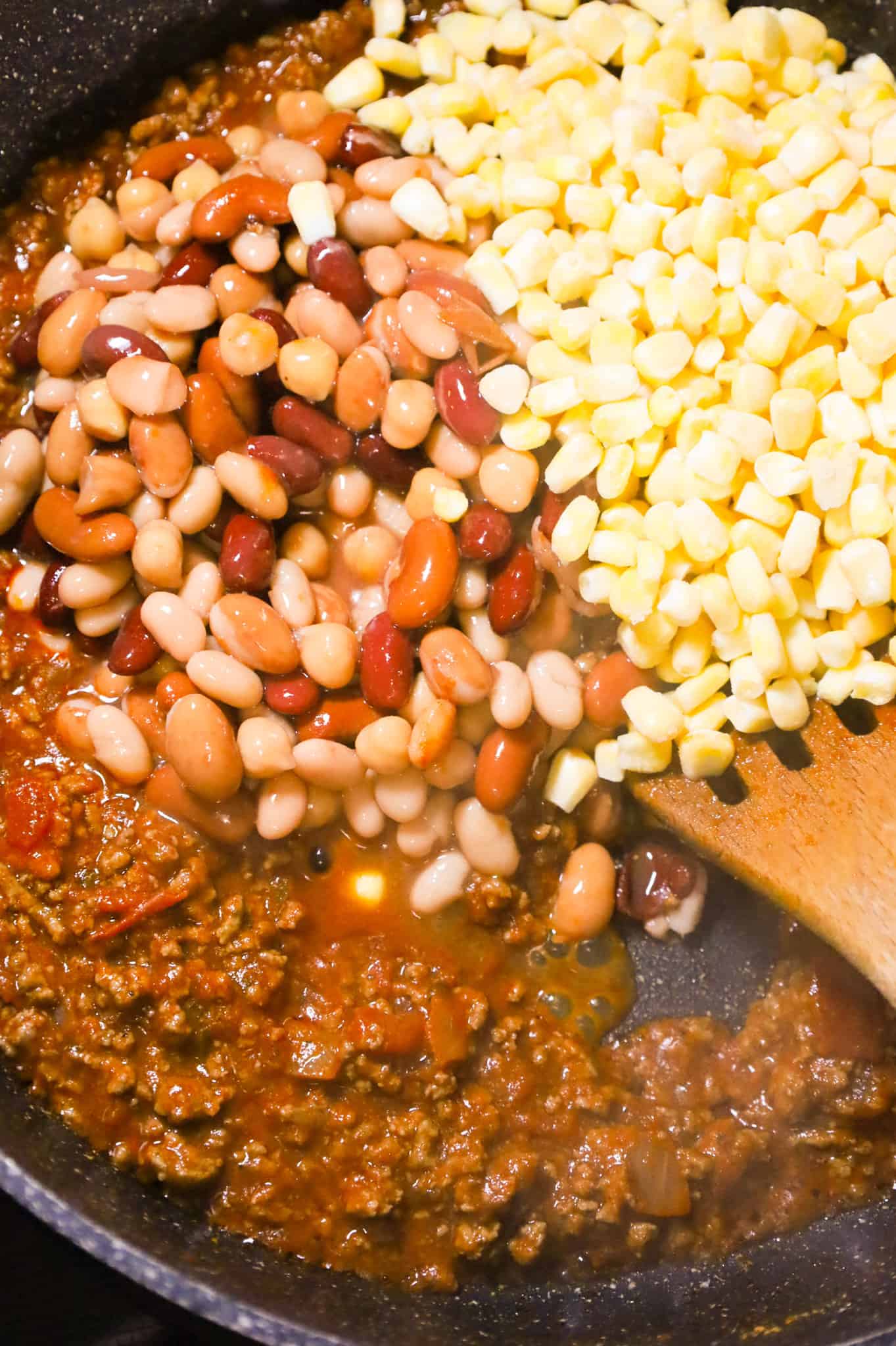 mixed beans and corn on top of ground beef and salsa mixture in a skillet