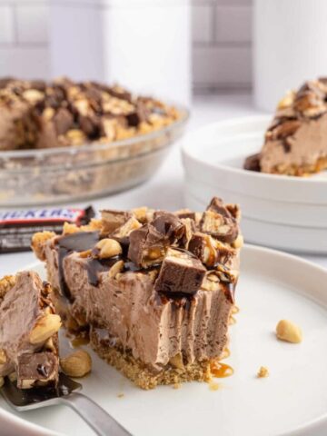 Snickers Pie is a delicious no bake dessert recipe with a graham cracker crust and a creamy filling made with cream cheese, cocoa powder, caramel sauce and Cool Whip all loaded with salted peanuts and chopped Snickers candy bars.