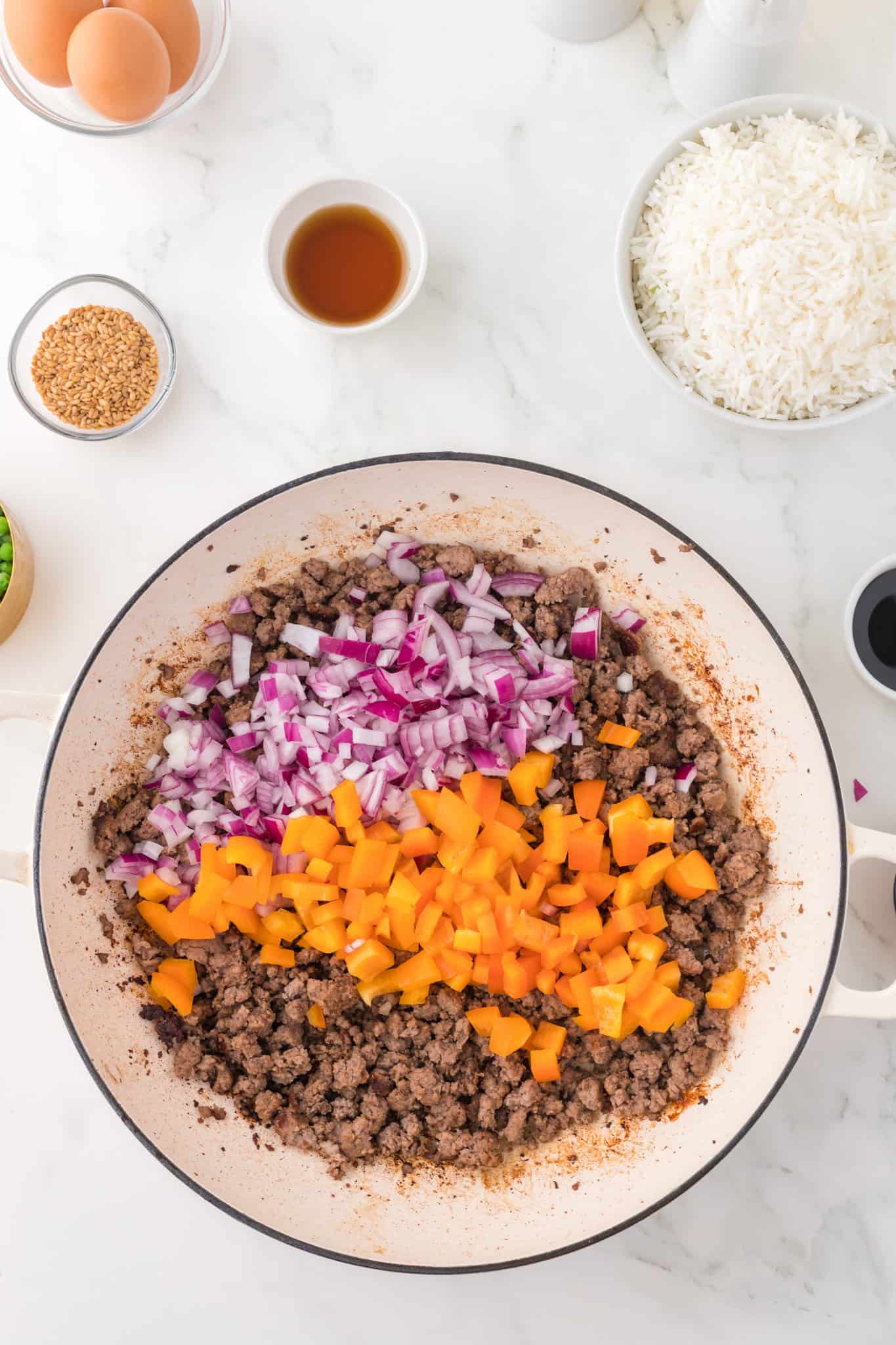 diced orange bell peppers and red onions added to skillet with cooked ground beef