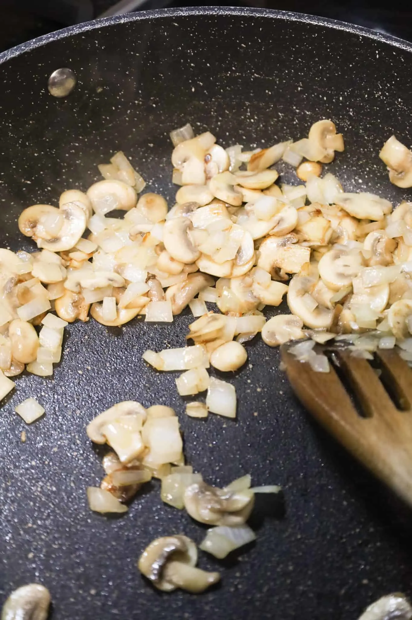 sliced mushrooms and diced onions browning in a skillet