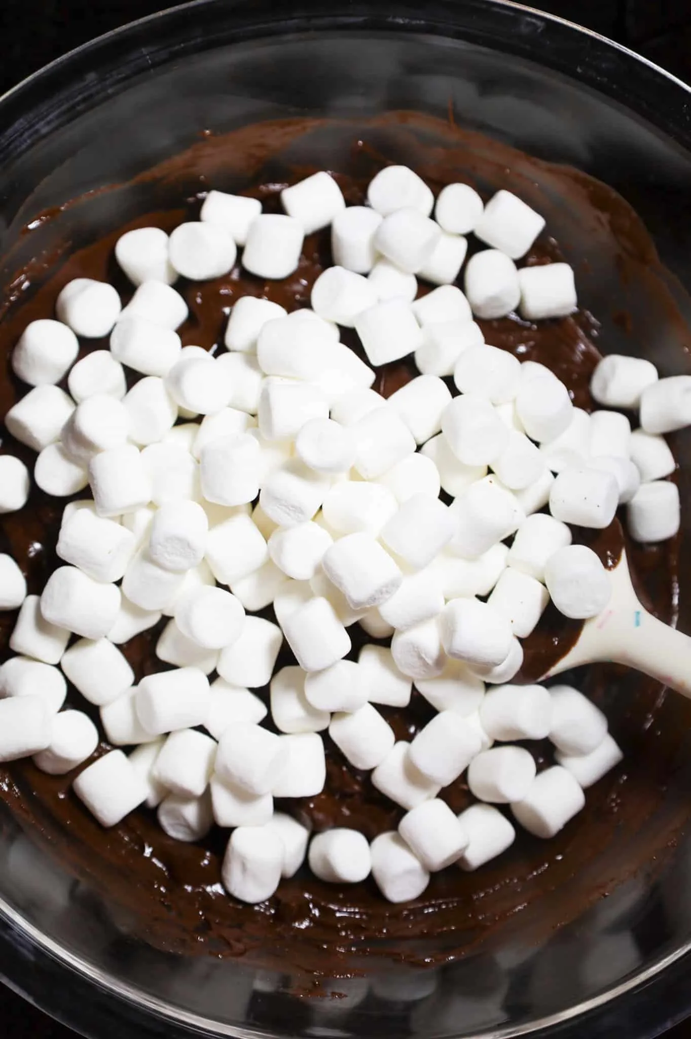 mini marshmallows added to bowl with chocolate and walnut mixture in a mixing bowl