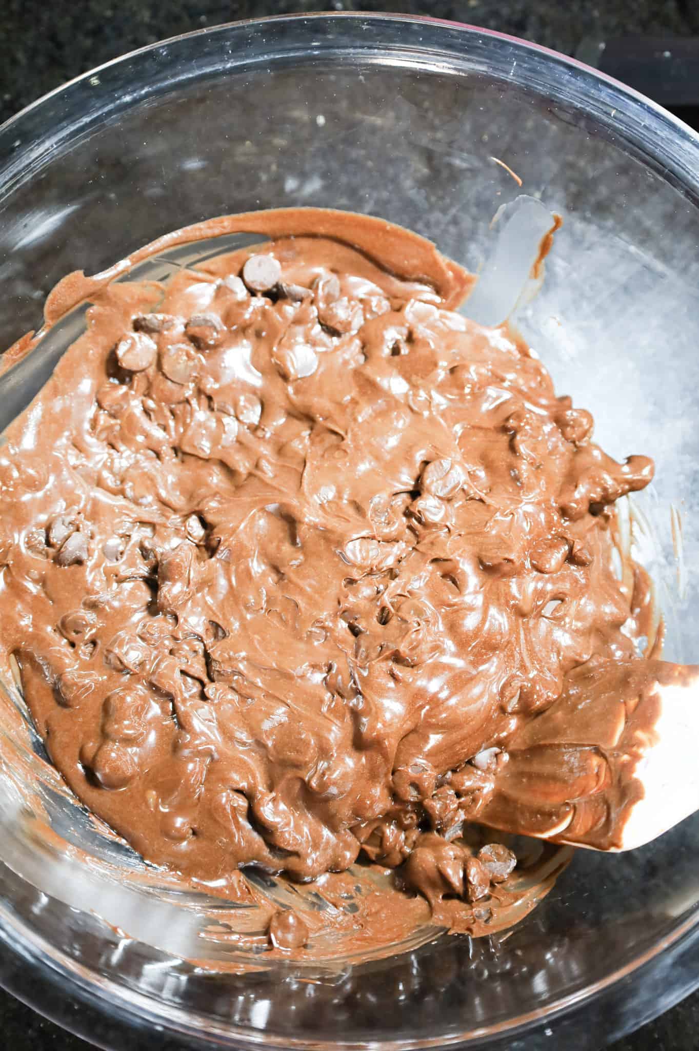 stirring chocolate chips and frosting together in a glass bowl