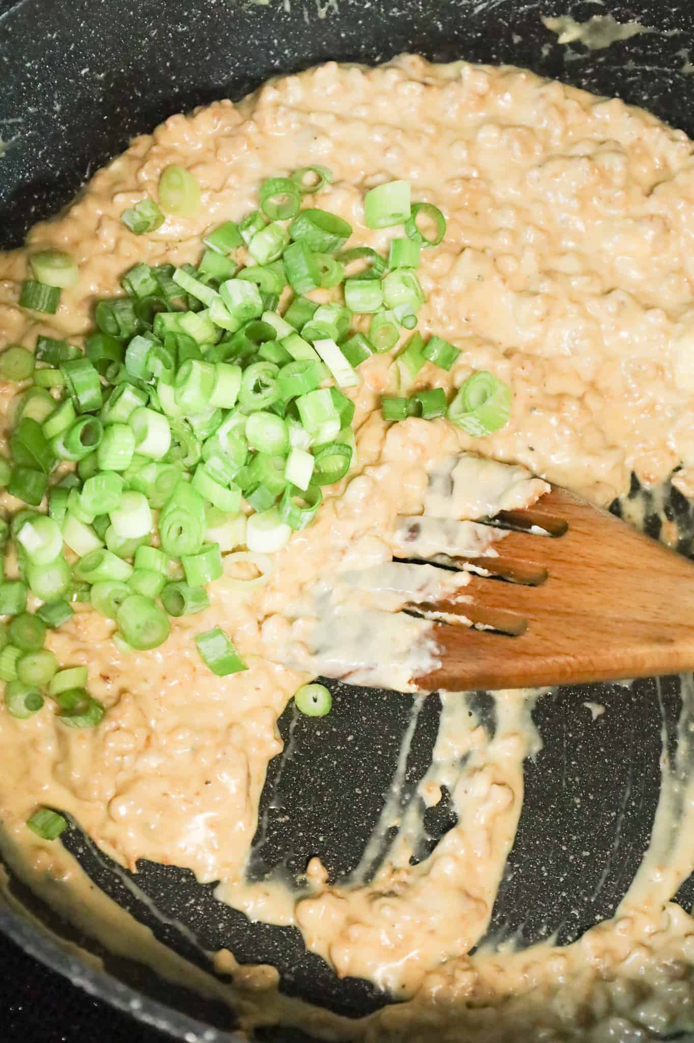 chopped green onions on top of cream cheese and sausage mixture in a skillet