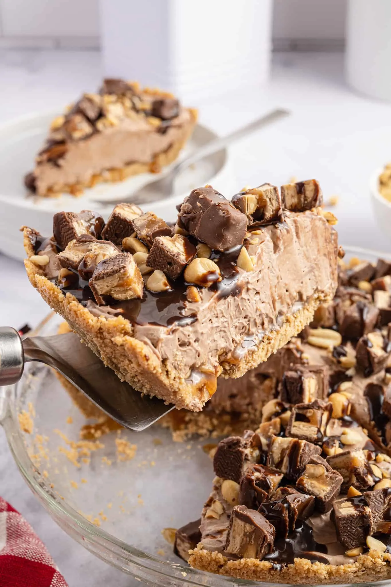 Snickers Pie is a delicious no bake dessert recipe with a graham cracker crust and a creamy filling made with cream cheese, cocoa powder, caramel sauce and Cool Whip all loaded with salted peanuts and chopped Snickers candy bars.