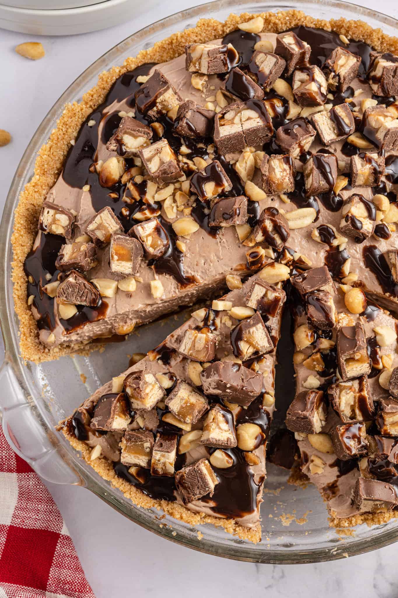 Snickers Pie is a delicious no bake dessert recipe with a graham cracker crust and a creamy filling made with cream cheese, cocoa powder, caramel sauce and Cool Whip all loaded with salted peanuts and chopped Snickers candy bars.