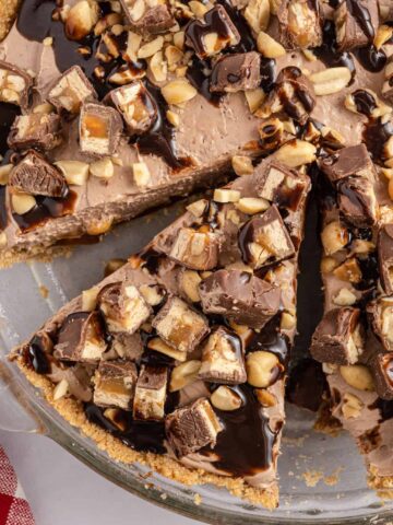 Snickers Pie is a delicious no bake dessert recipe with a graham cracker crust and a creamy filling made with cream cheese, cocoa powder, caramel sauce and Cool Whip all loaded with salted peanuts and chopped Snickers candy bars.
