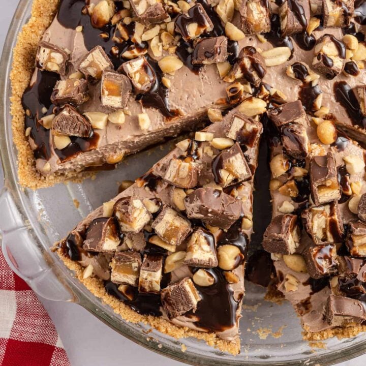 Snickers Pie is a delicious no bake dessert recipe with a graham cracker crust and a creamy filling made with cream cheese, cocoa powder, caramel sauce and Cool Whip all loaded with salted peanuts and chopped Snickers candy bars.