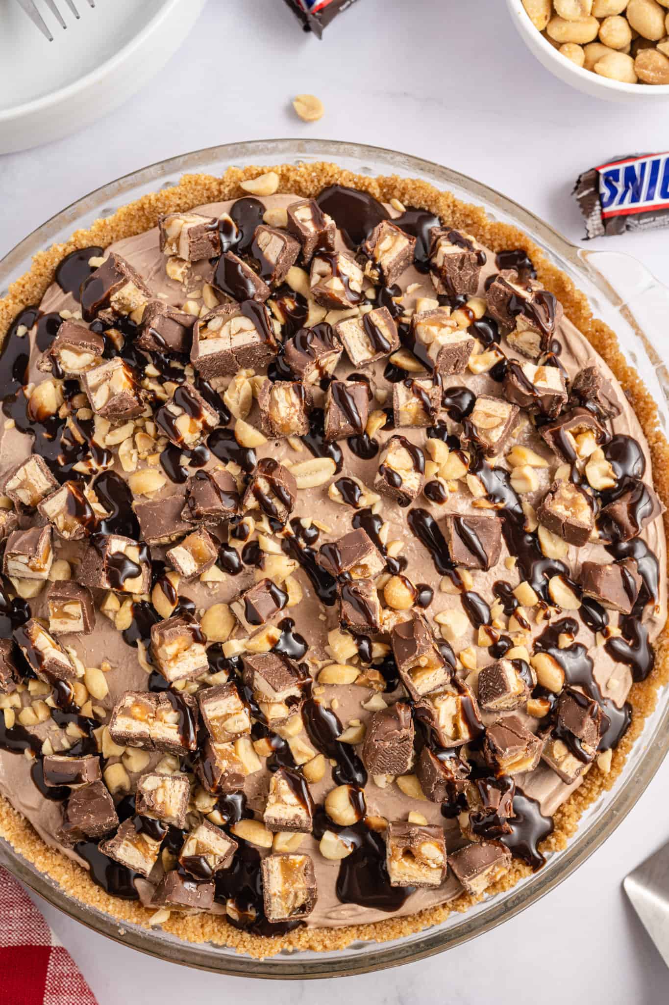 Snickers Pie is a delicious no bake dessert recipe with a graham cracker crust and a creamy filling made with cream cheese, cocoa powder, caramel sauce and Cool Whip all loaded with salted peanuts and chopped Snickers candy bars.