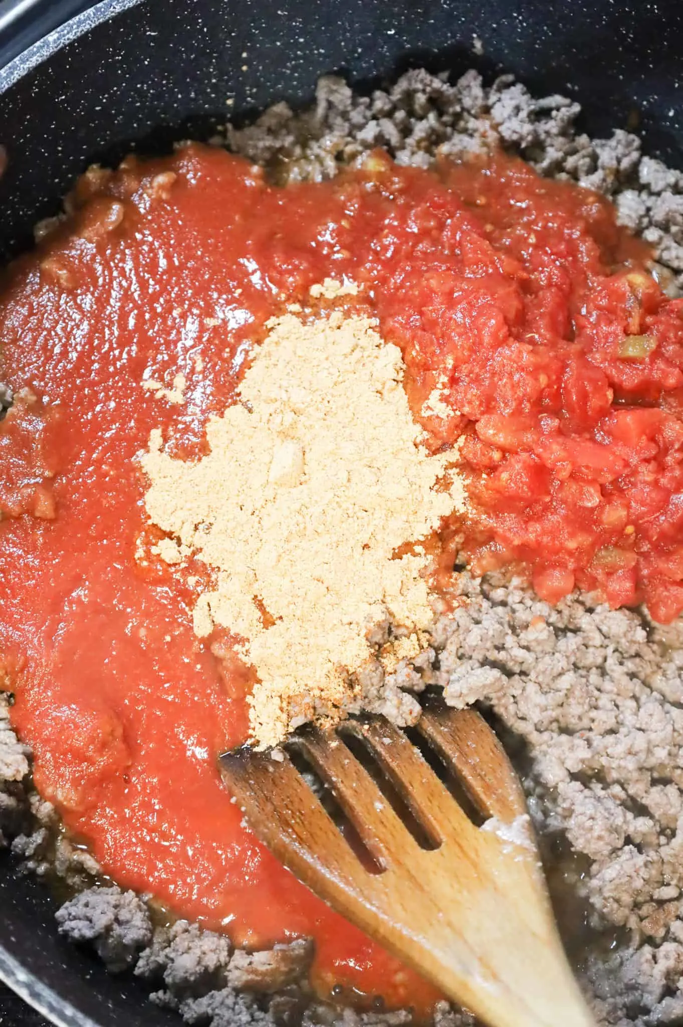 taco seasoning, Rotel and tomato sauce on top of cooked ground beef in a skillet
