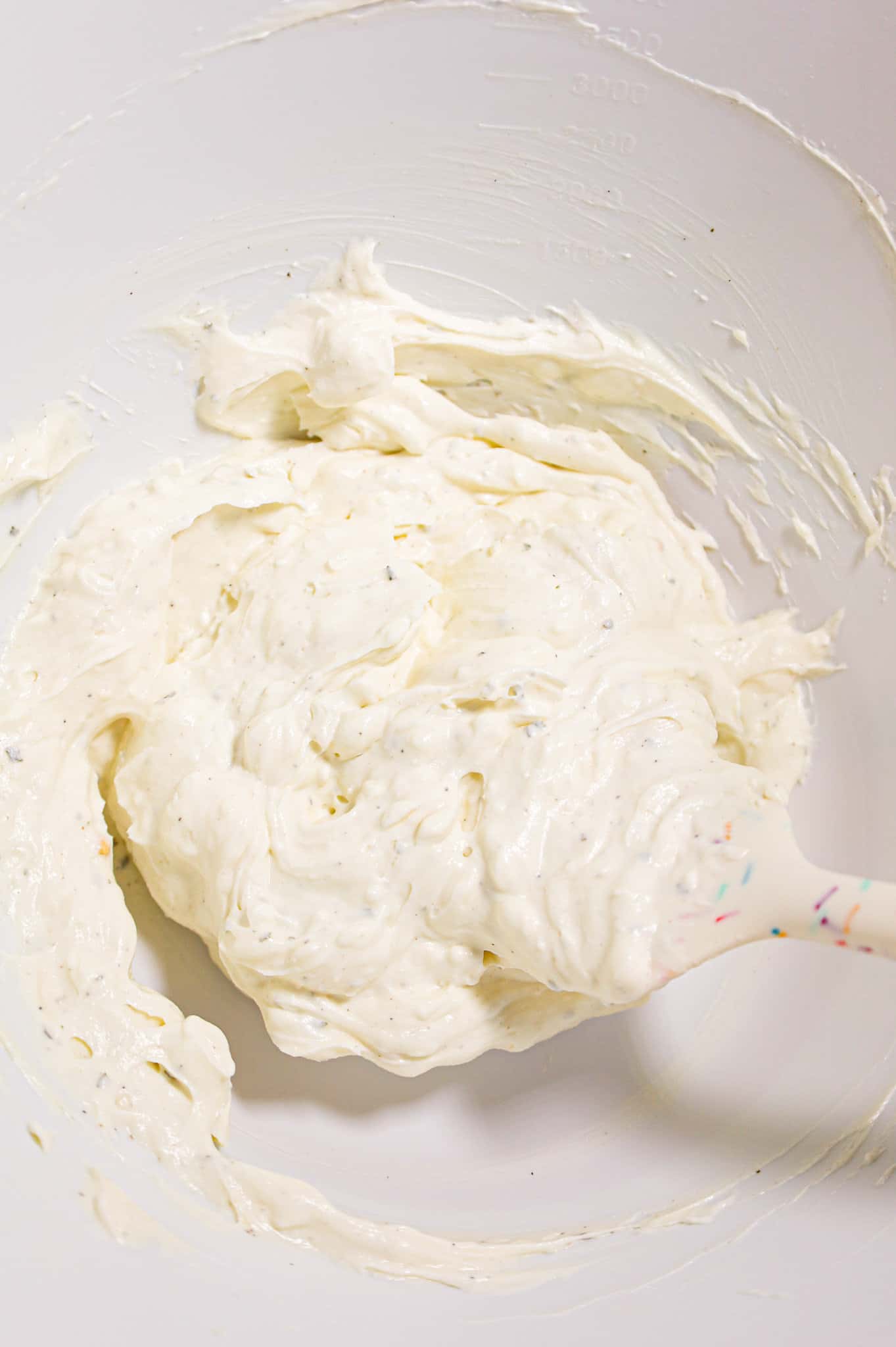 cream cheese and sour cream being stirred together in a mixing bowl