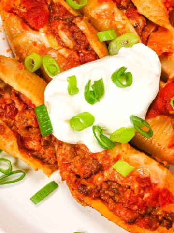 Taco Stuffed Shells are cheesy ground beef stuffed pasta shells loaded with salsa and Rotel diced tomatoes and green chilies.