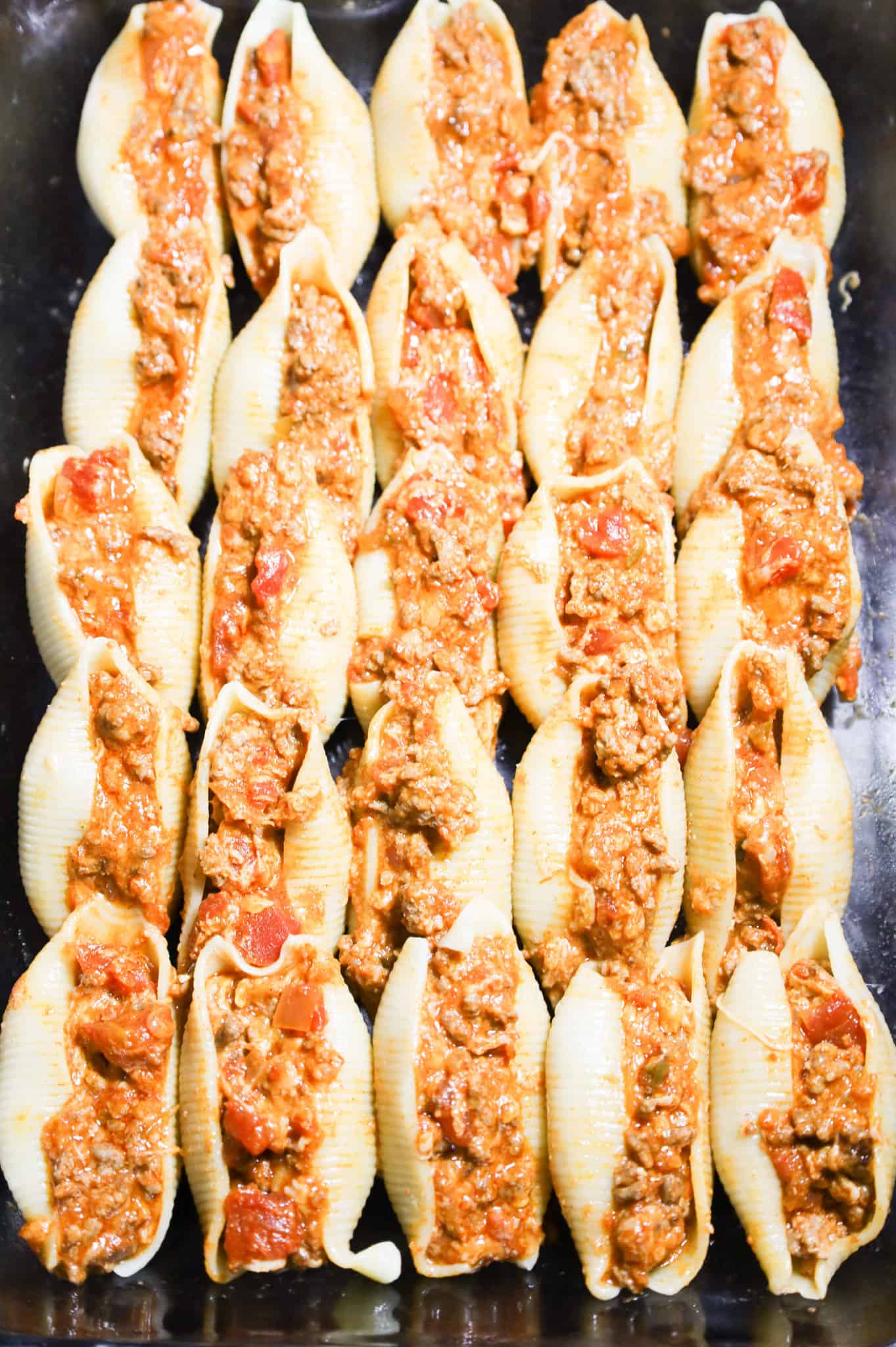 pasta shells in a baking dish stuffed with a cheesy ground beef mixture.