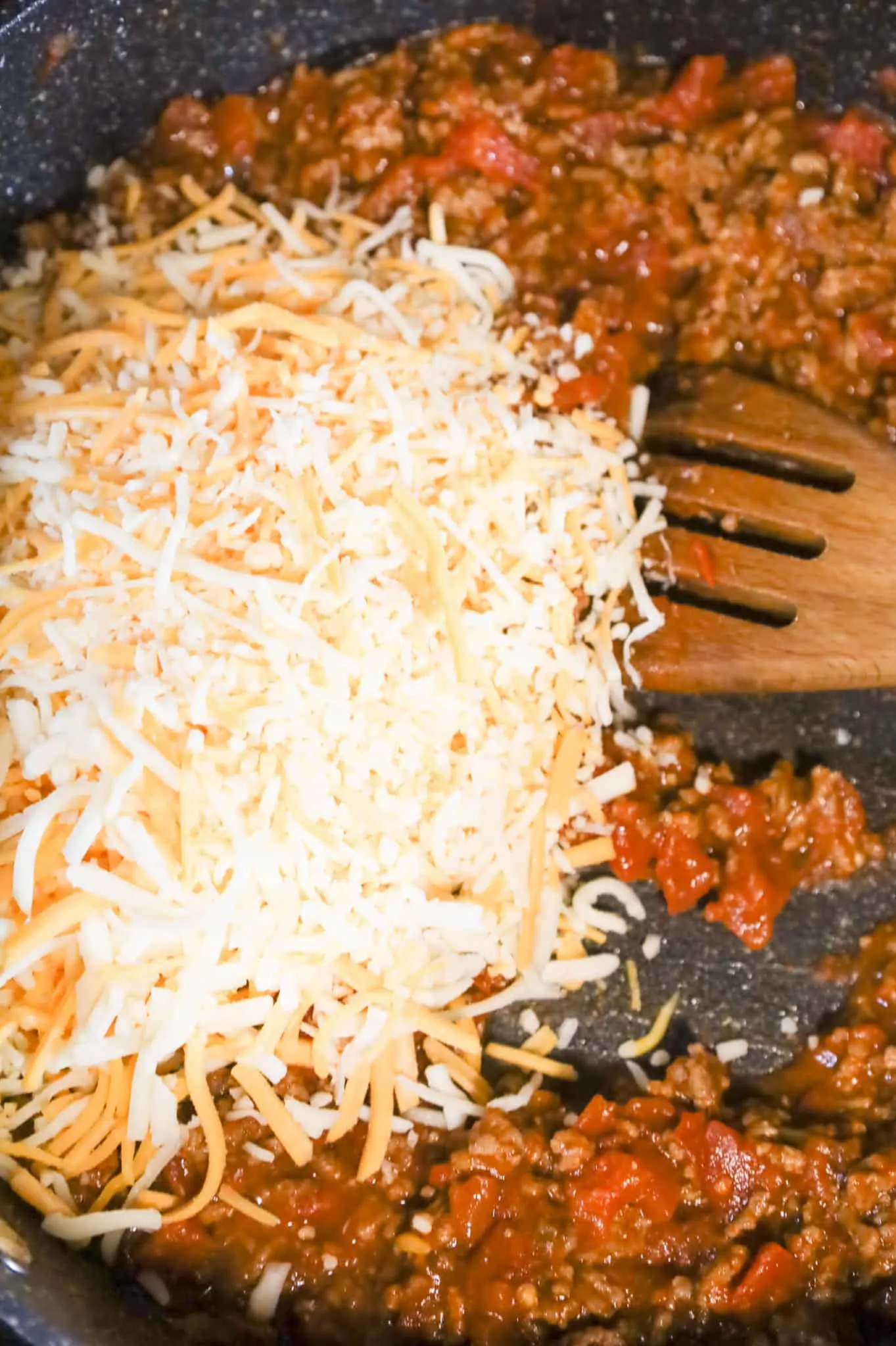 shredded cheese on top of ground beef and salsa mixture in a skillet