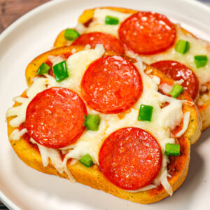 Texas Toast Pizza is an easy weeknight dinner recipe using frozen Texas toast garlic bread and topped with pizza sauce, shredded mozzarella cheese, pepperoni slices and green peppers.