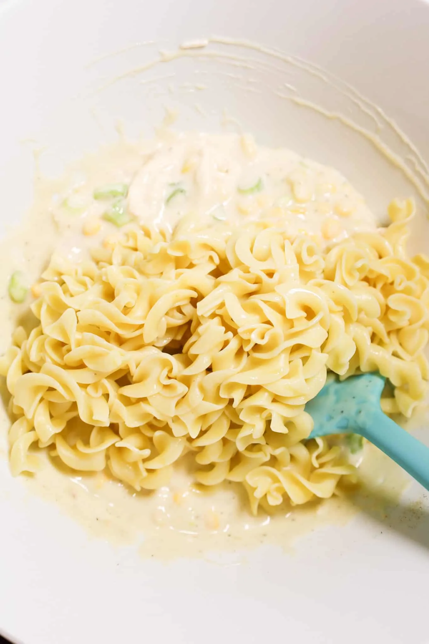 cooked egg noodles on top of creamy soup mixture in a mixing bowl