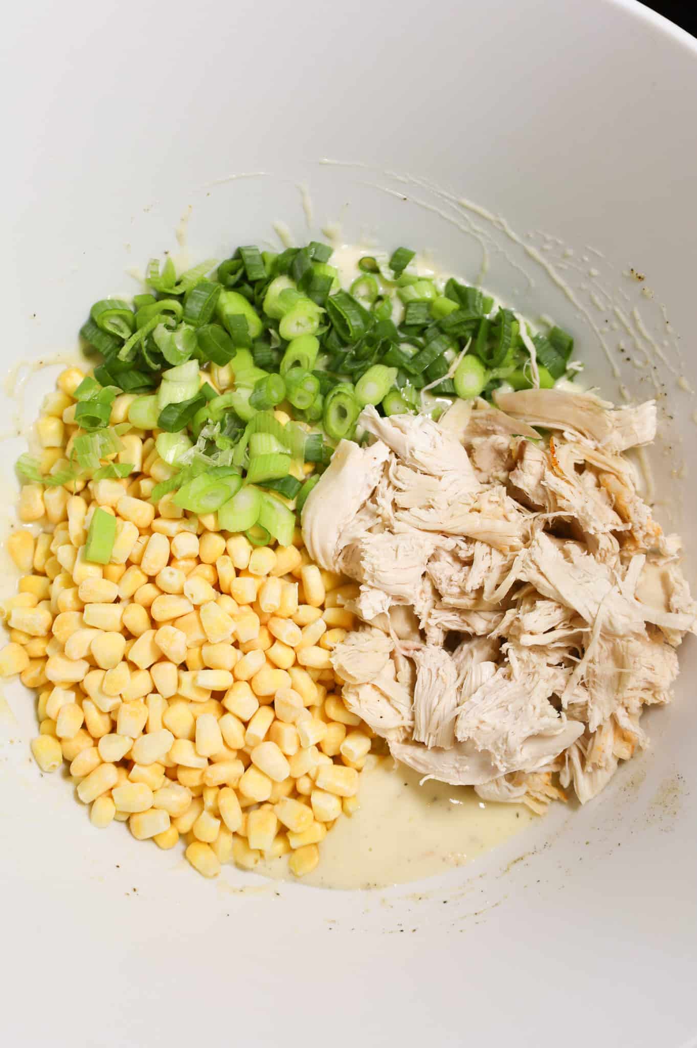 shredded chicken, chopped green onions and frozen corn on top of creamy soup mixture in a mixing bowl