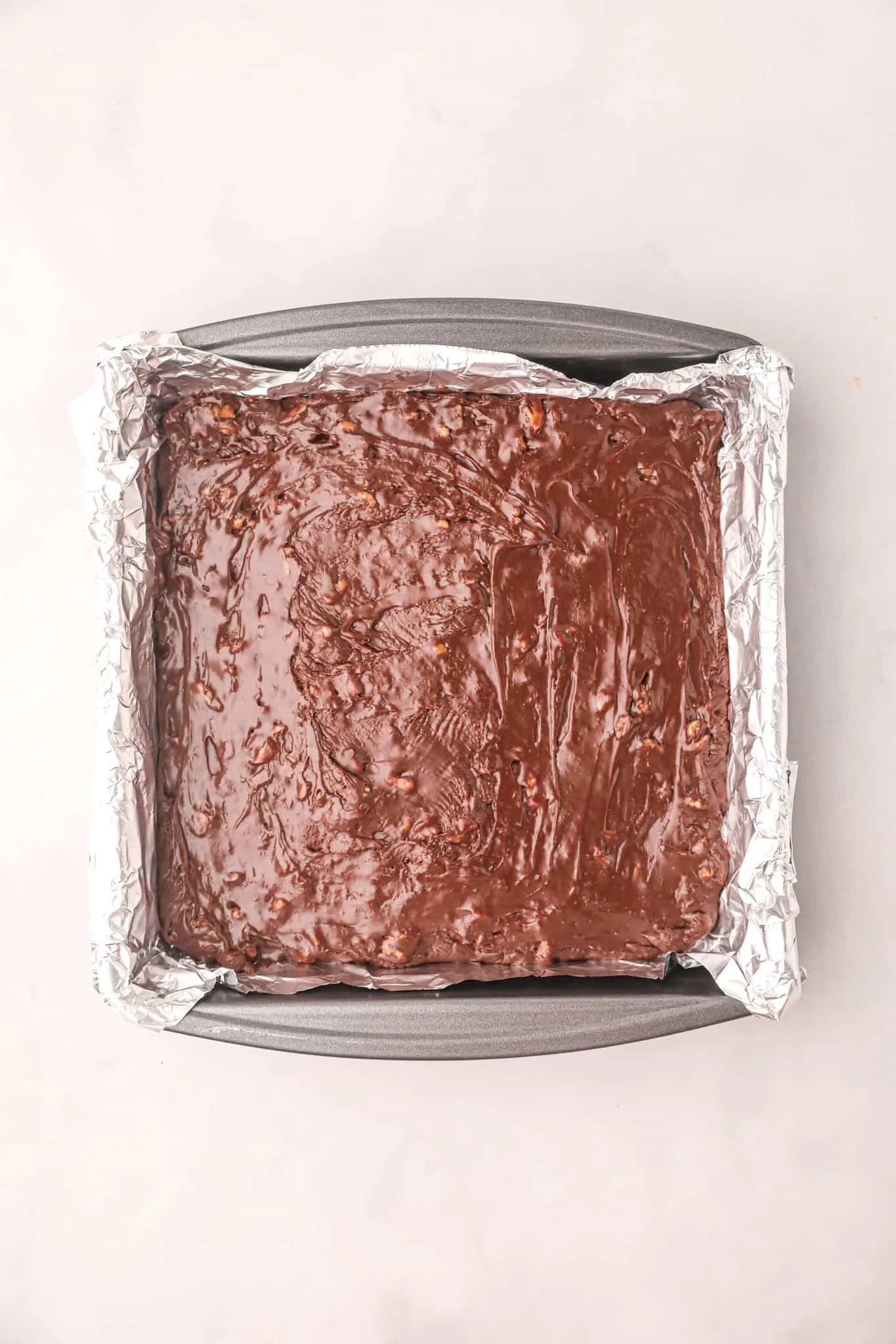 chocolate walnut fudge mixture in a foil lined pan