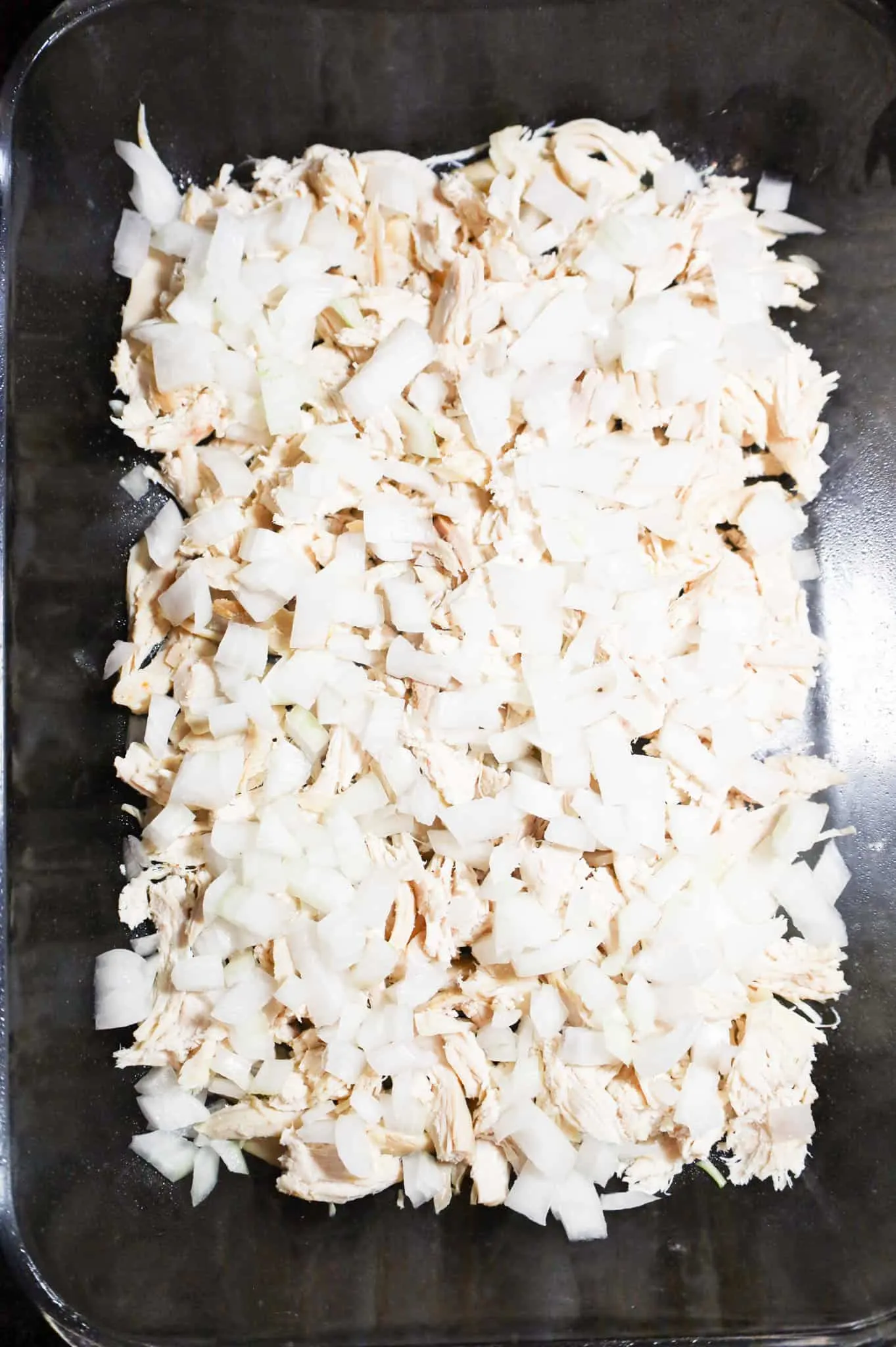 diced onions and shredded chicken in a baking dish
