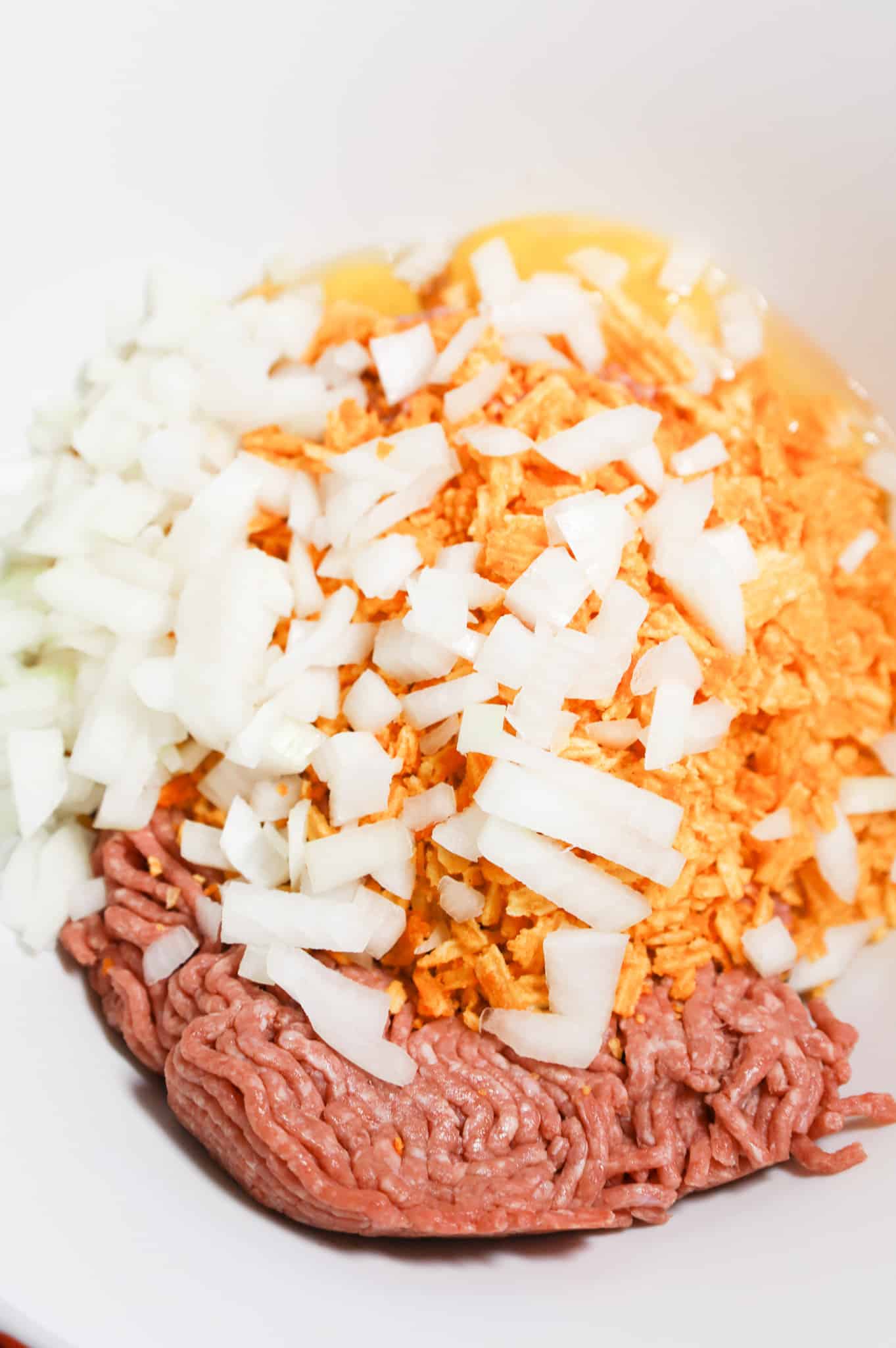 diced onions, crushed bbq potato chips and ground beef in a mixing bowl