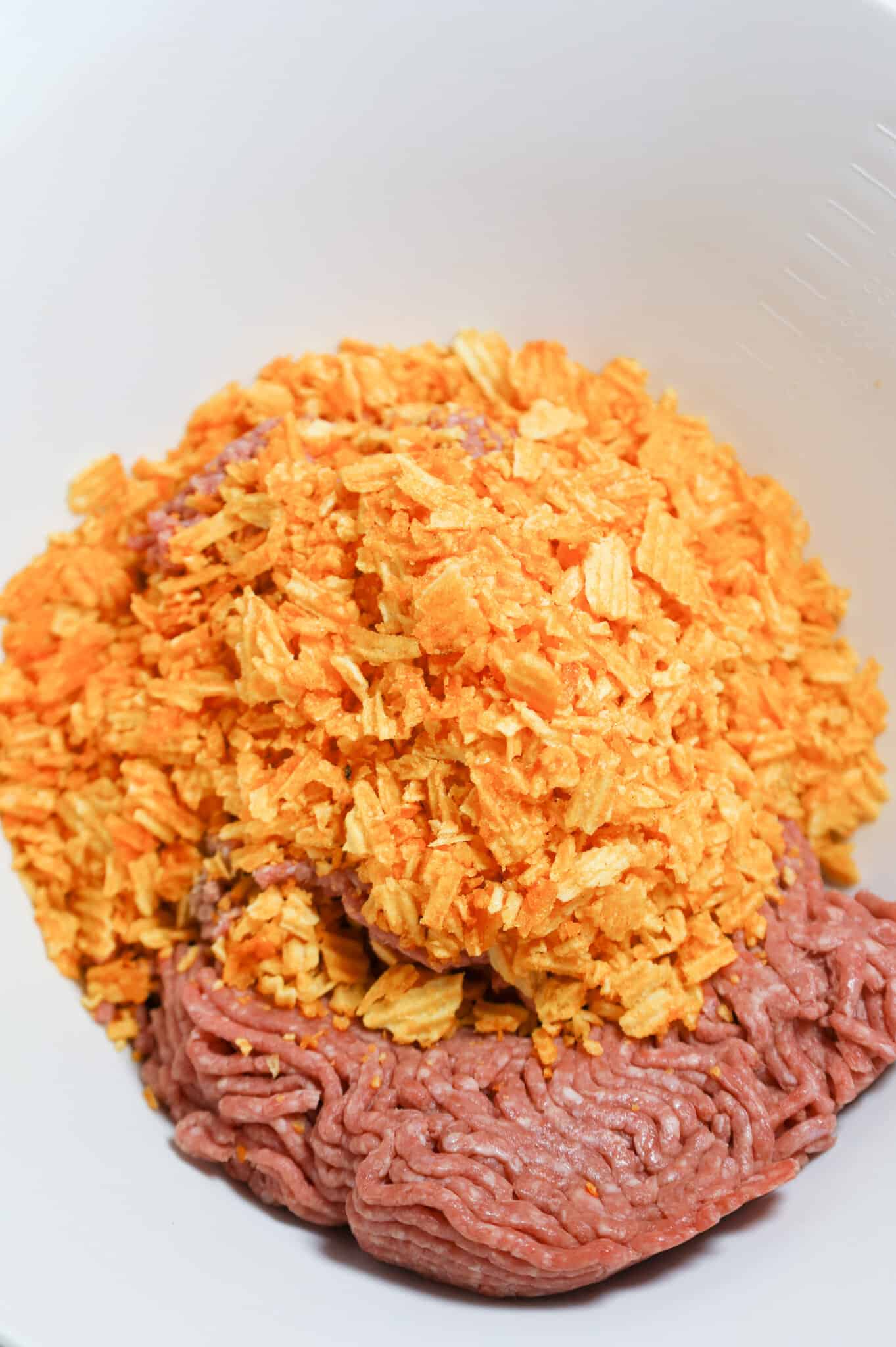 crushed bbq potato chips on top of ground beef in a mixing bowl