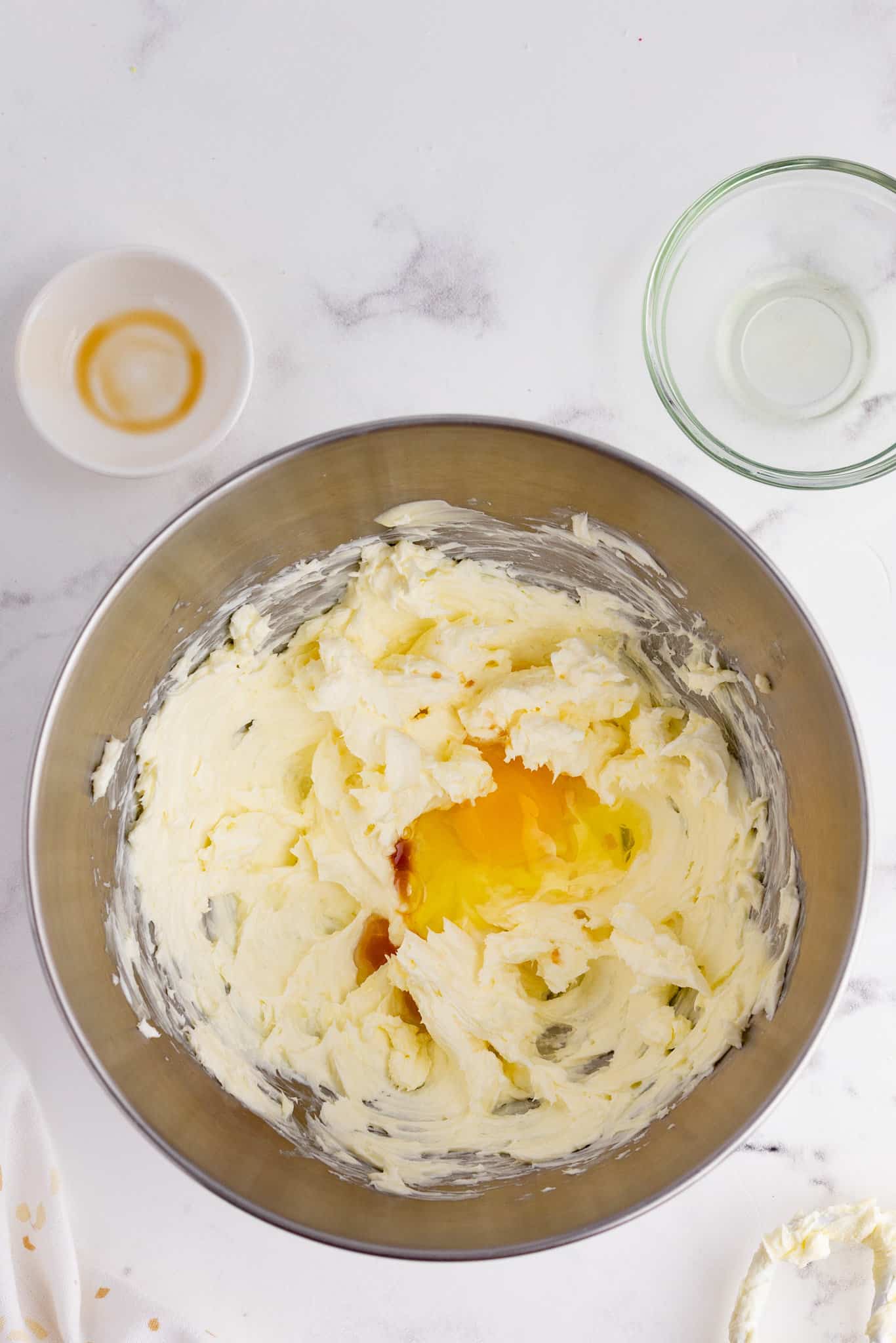 an egg and vanilla extract added to mixing bowl with creamed butter and cream cheese mixture