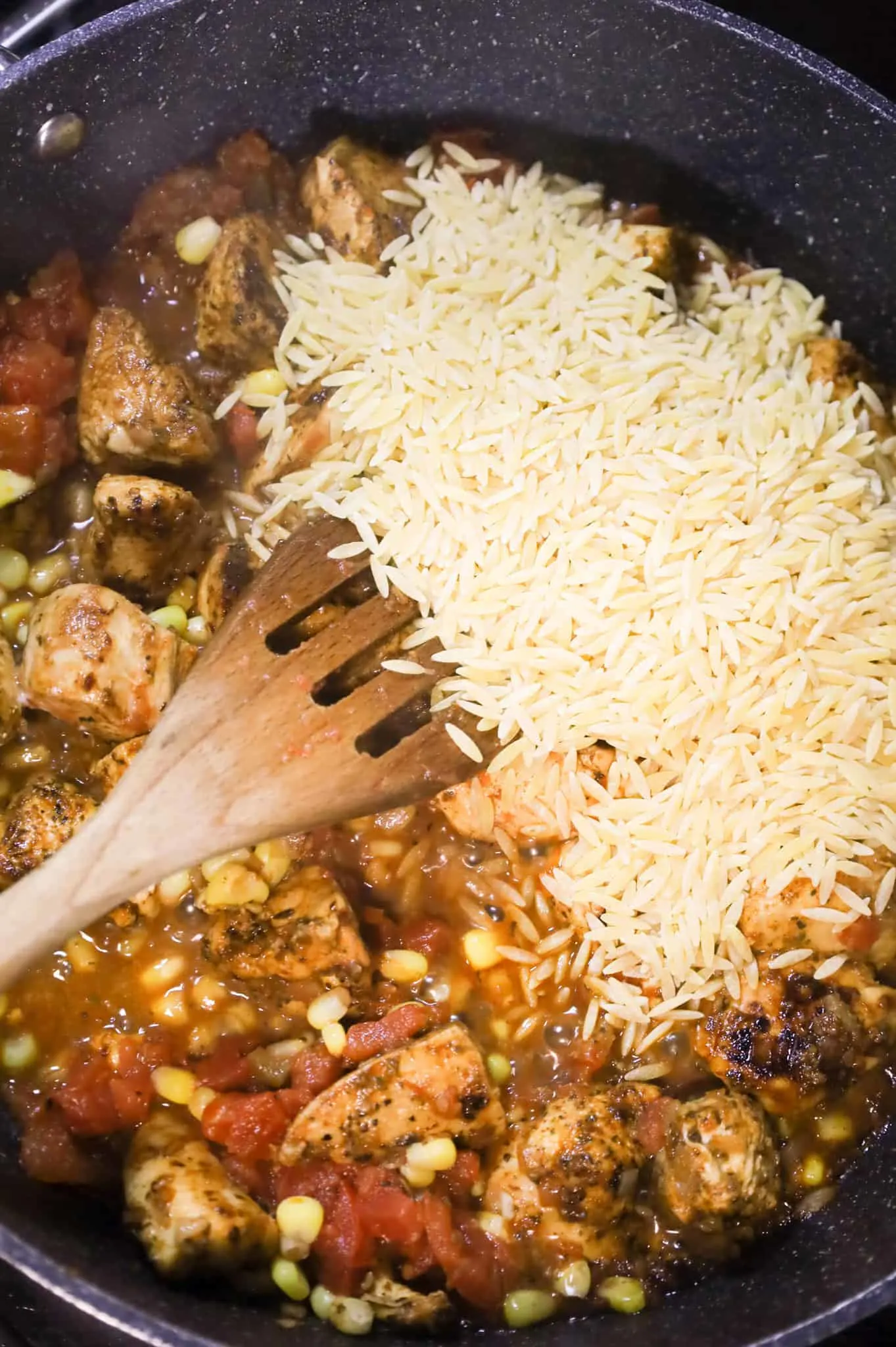 orzo pasta on top of chicken, Rotel and corn in a skillet