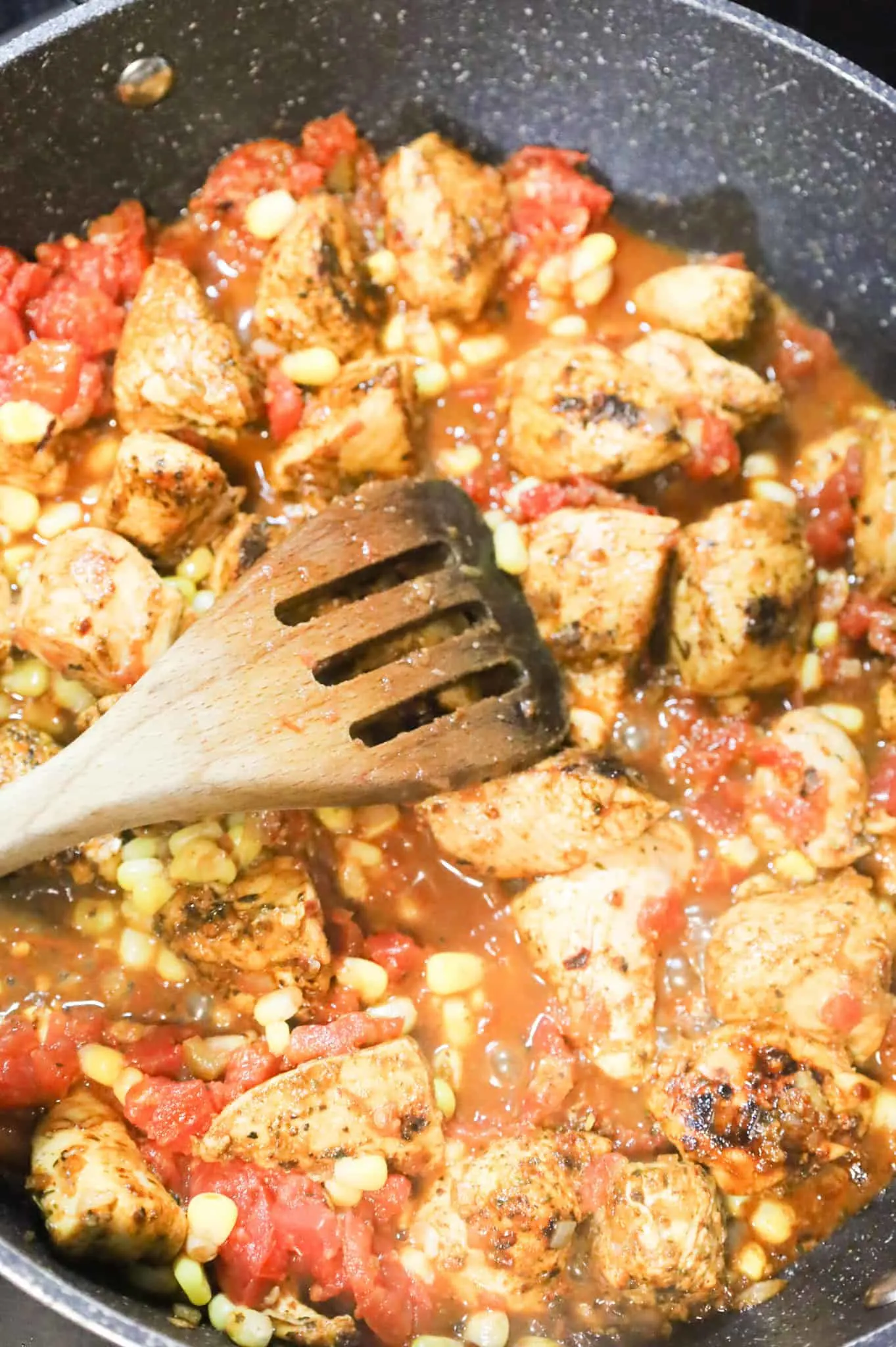 stirring together frozen corn, Rotel and chicken breast chunks in a skillet