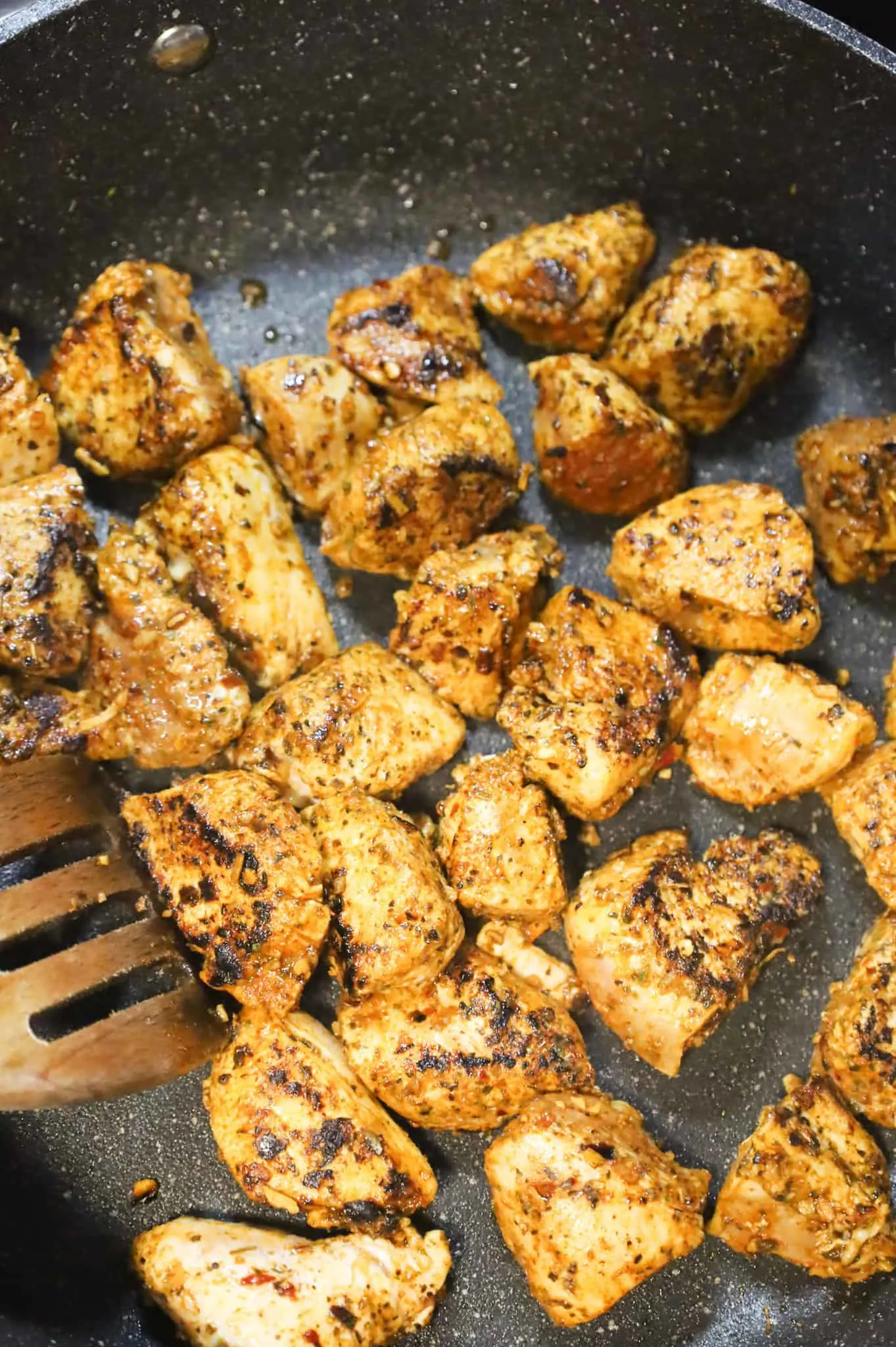stirring chicken breast chunks while cooking in a skillet