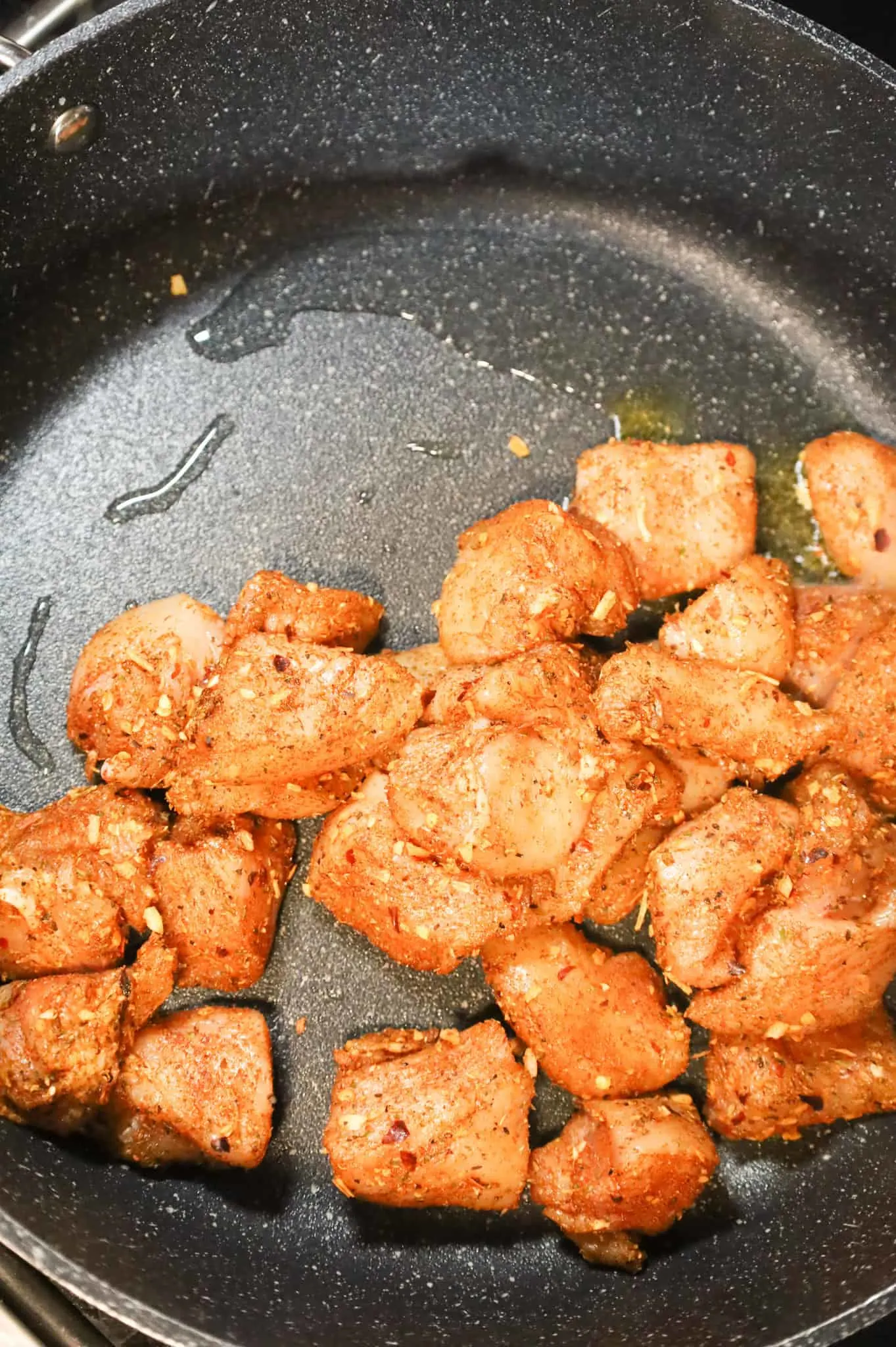 Cajun seasoned chicken breast chunks added to a hot skillet