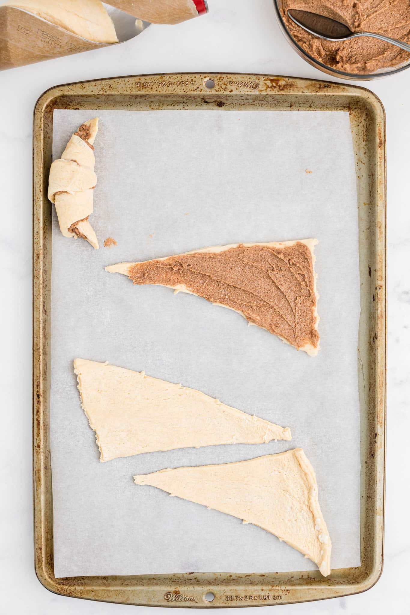 cinnamon mixture spread on triangle of crescent dough