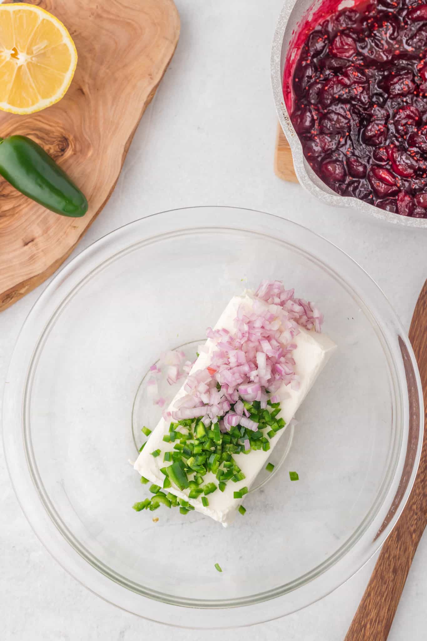 diced shallots and jalapenos on top of softened cream cheese in a mixing bowl