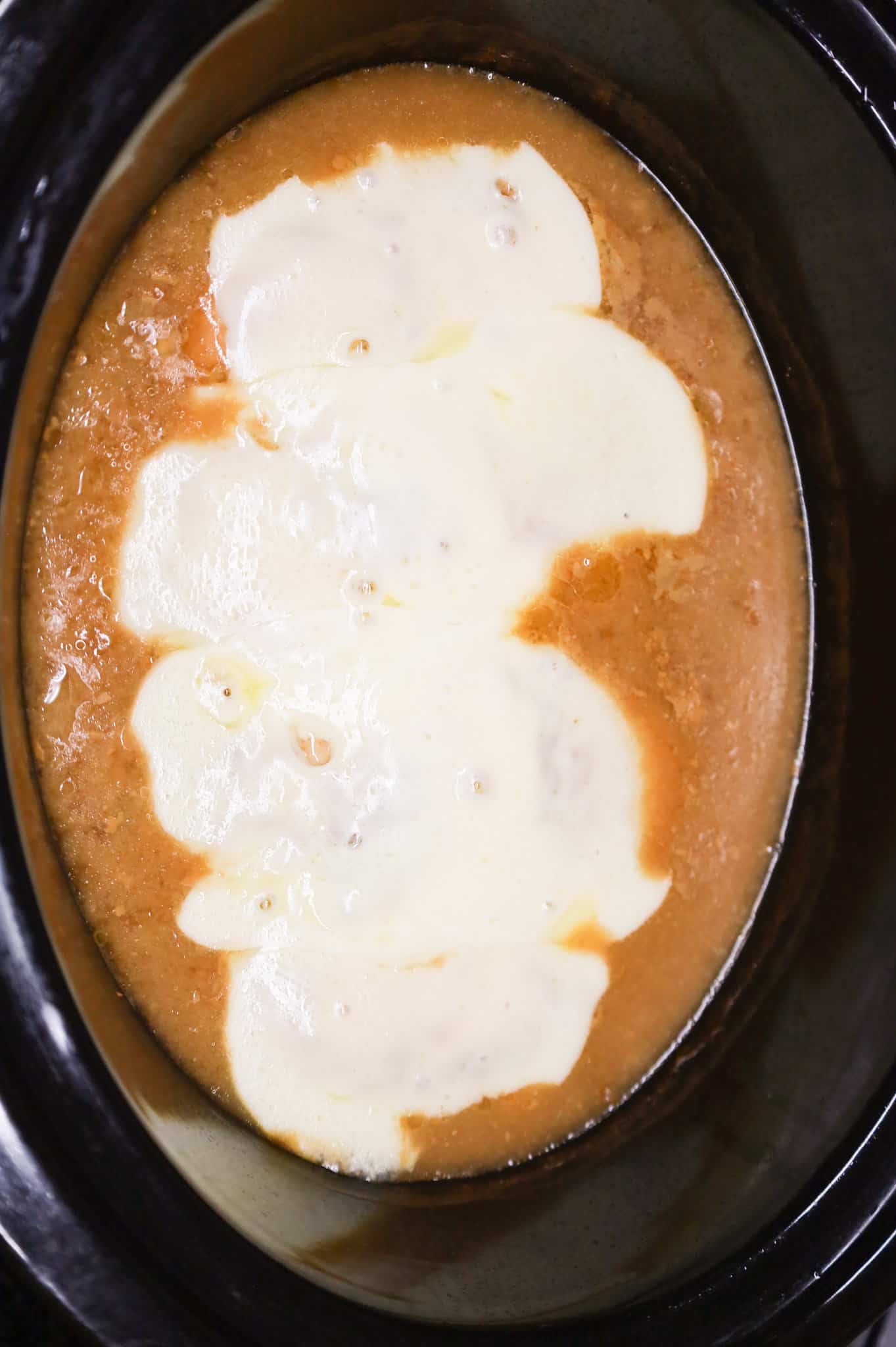 melted provolone cheese on top of French onion chicken in a Crock pot