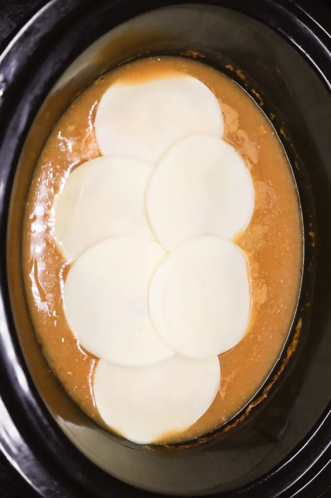 provolone cheese slices on top of French onion chicken in a Crock pot