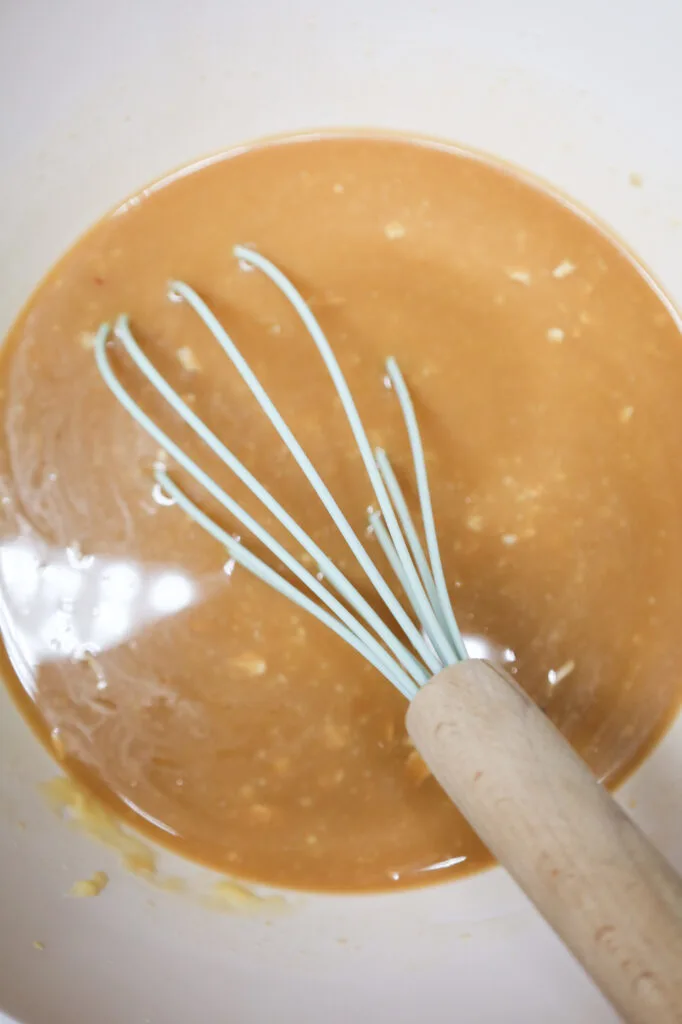 onion soup and beef broth mixture being whisked in a mixing bowl