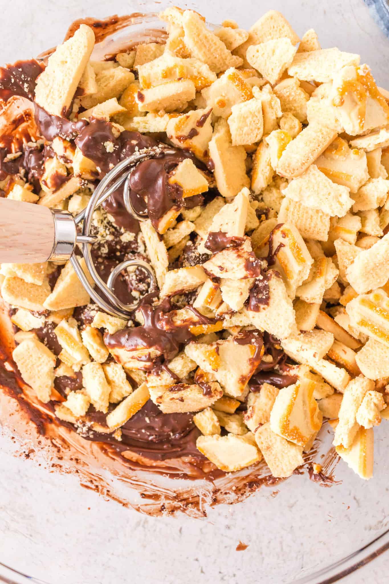 butter cookie pieces on top of chocolate mixture in a mixing bowl