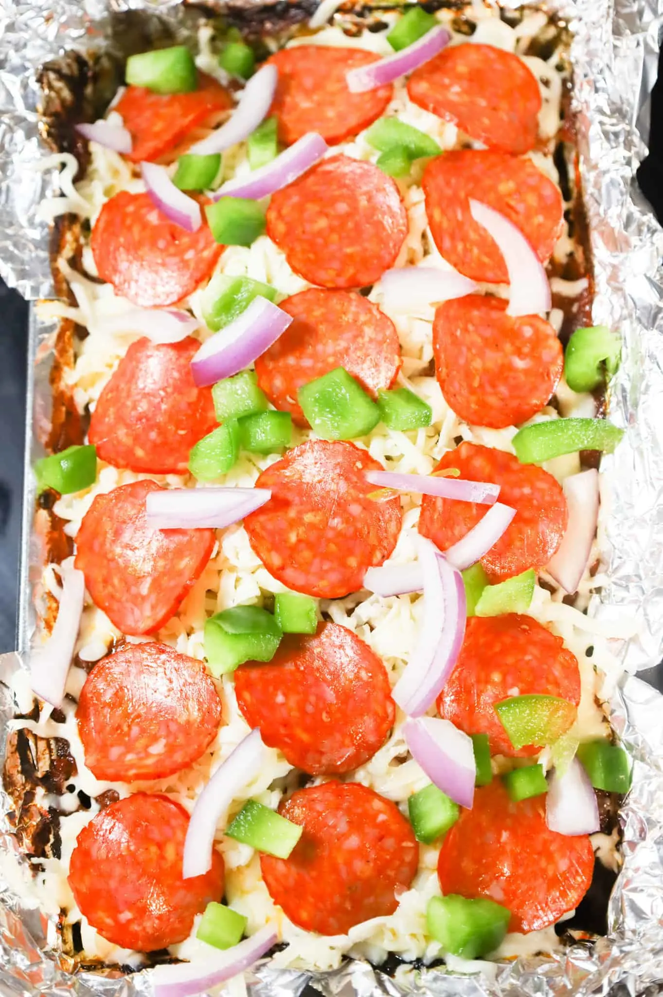 green peppers, red onions, pepperoni slices and mozzarella cheese on top of meatloaf