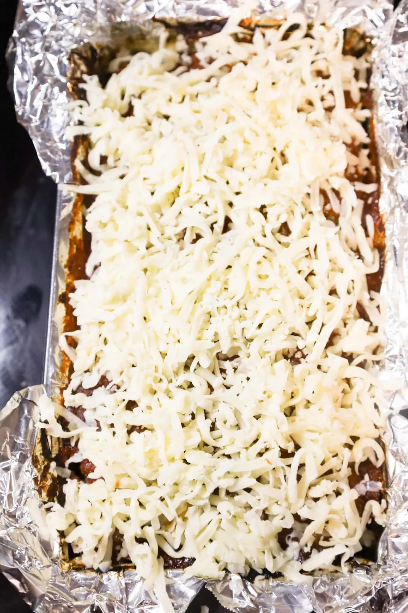 shredded mozzarella cheese on top of meatloaf in a pan