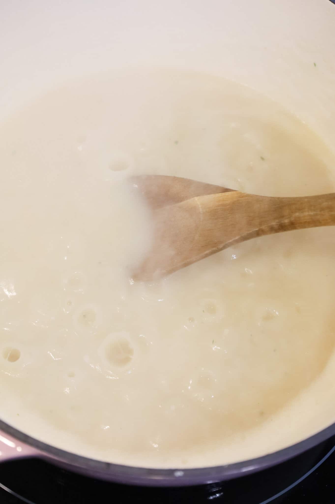 stirring together instant mashed potato mix and chicken broth in a large pot