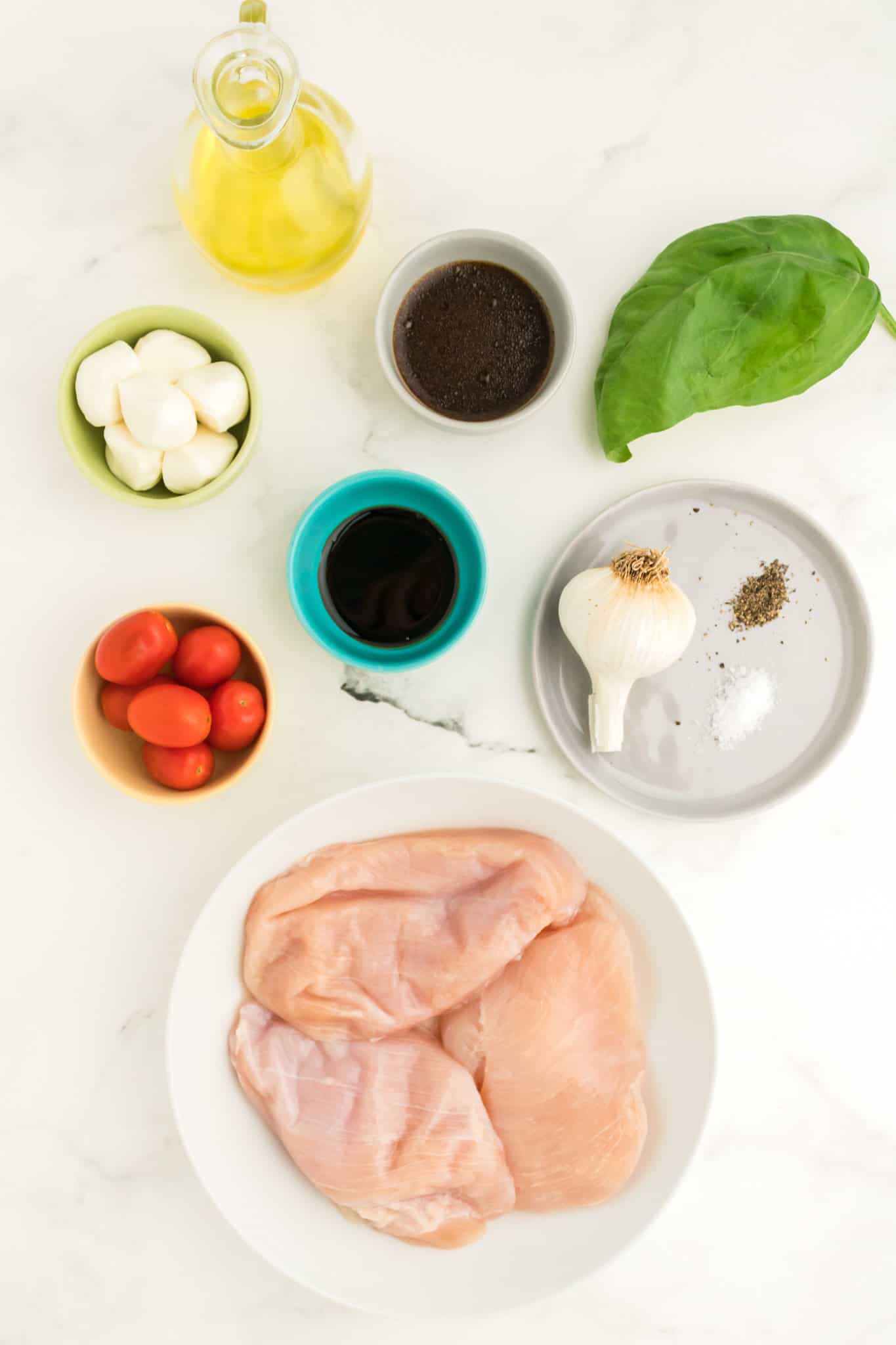 raw chicken breasts on a plate with other ingredients beside