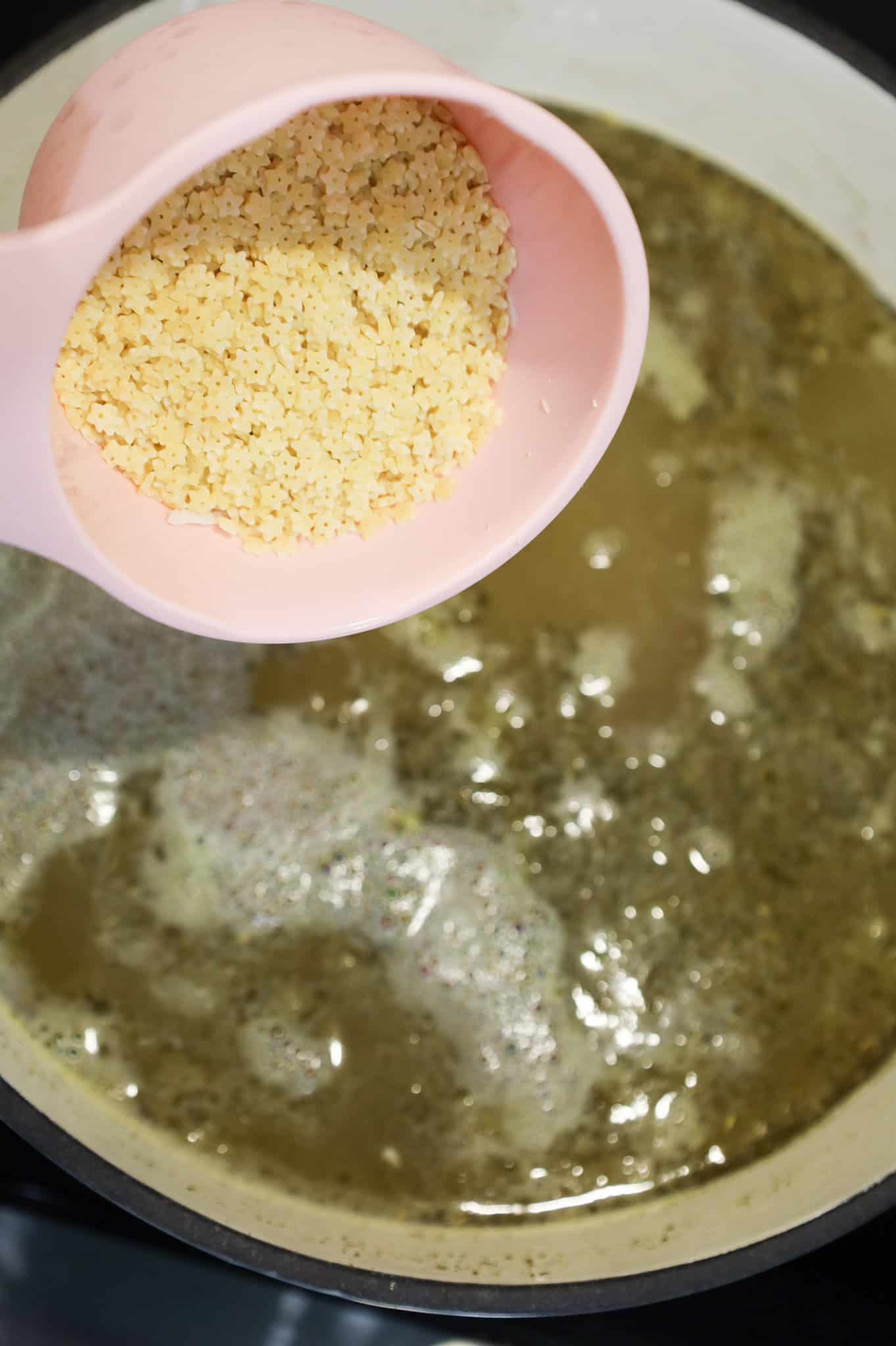 star shaped noodles being added to chicken soup in a pot