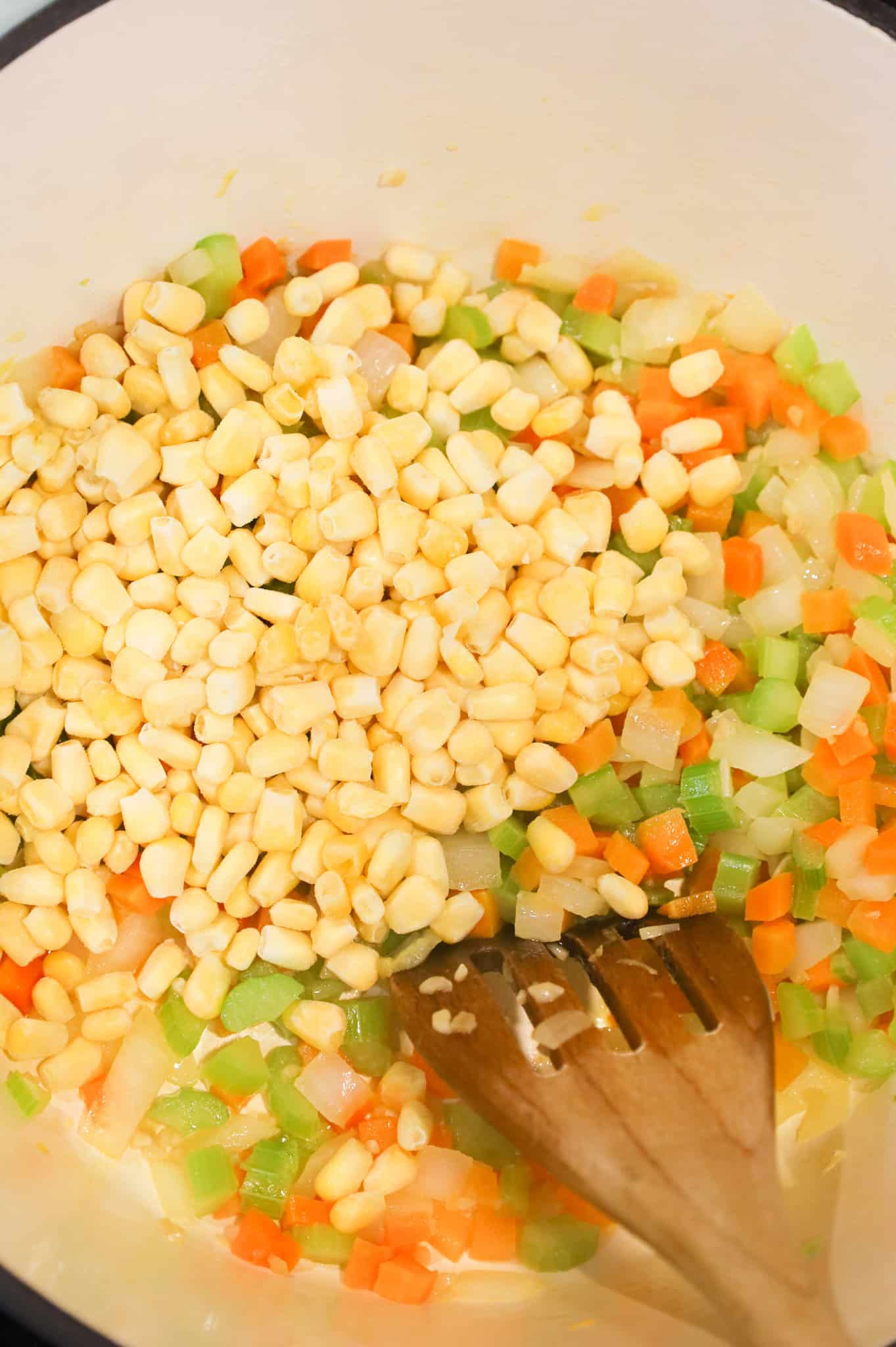 frozen corn kernels added to pot with diced onions, carrots and celery
