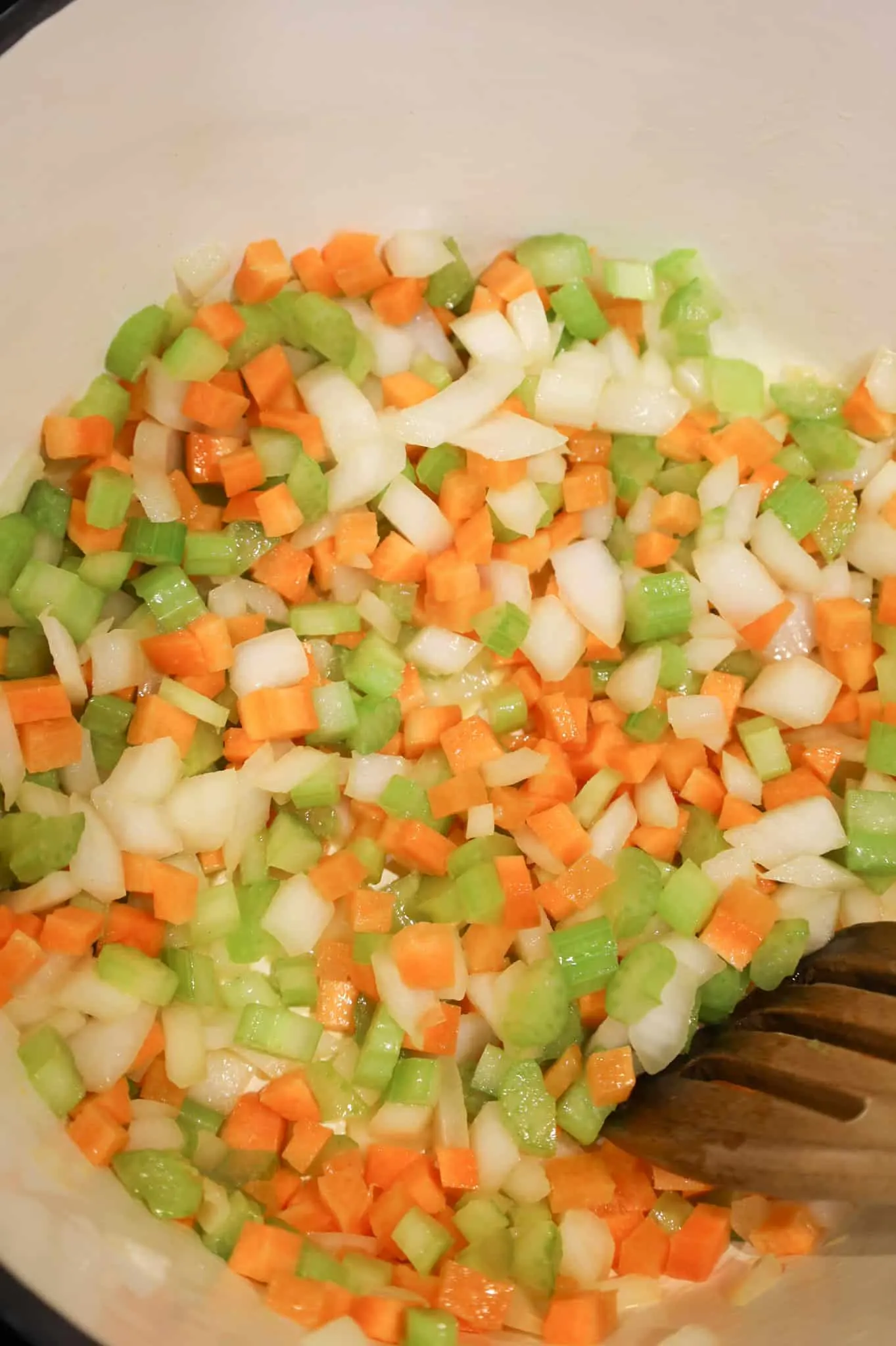 diced onions, carrots and celery being stirred in a pot
