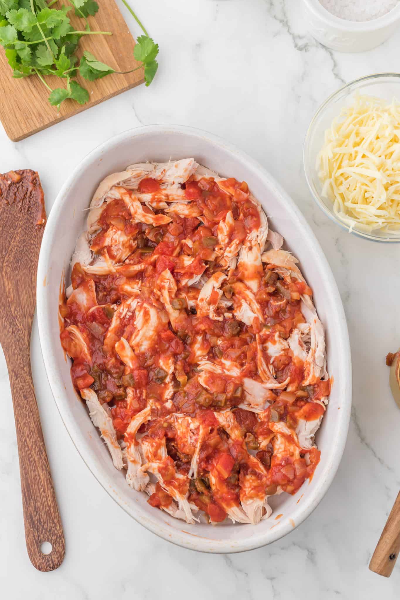 salsa on top of shredded chicken in a baking dish