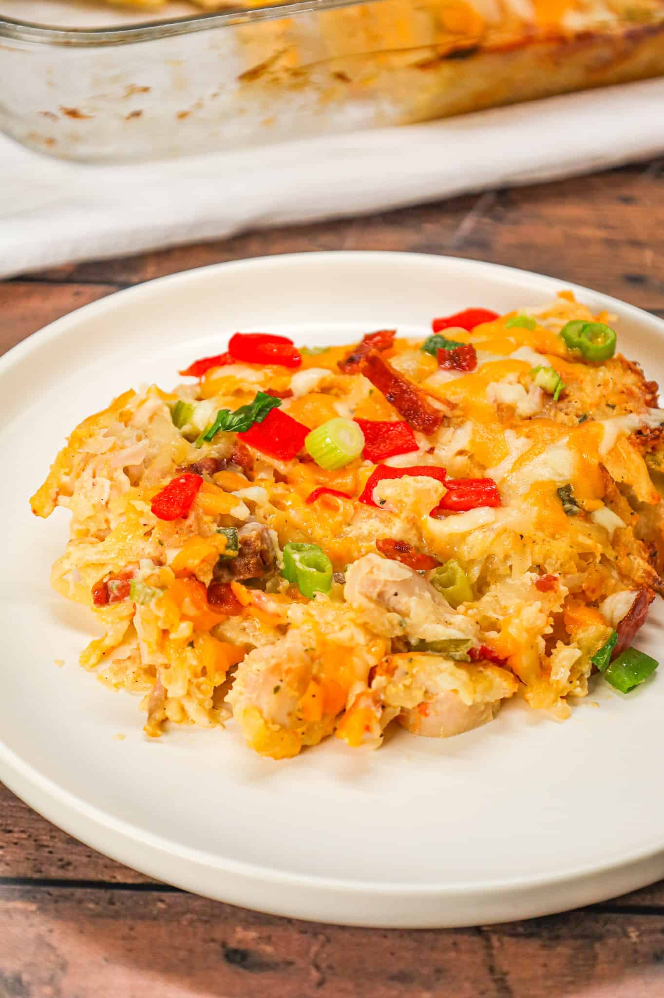 Chicken Hashbrown Casserole is a hearty dish made with shredded potatoes, shredded rotisserie chicken, crumbled bacon, roasted red peppers, cheddar cheese, ranch dressing mix, sour cream and cream of chicken soup.