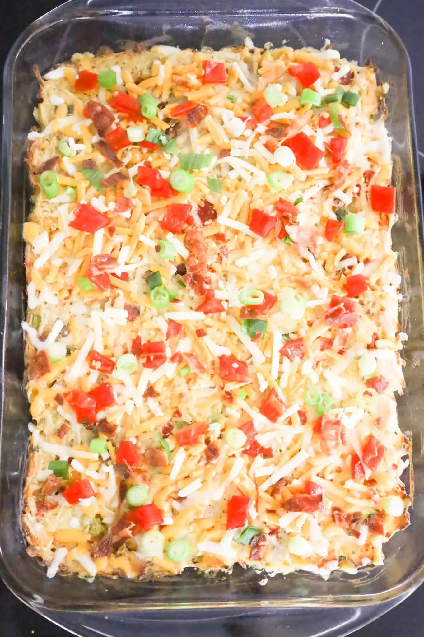 roasted red peppers, chopped green onions, crumbled bacon and shredded cheese on top of a hashbrown casserole