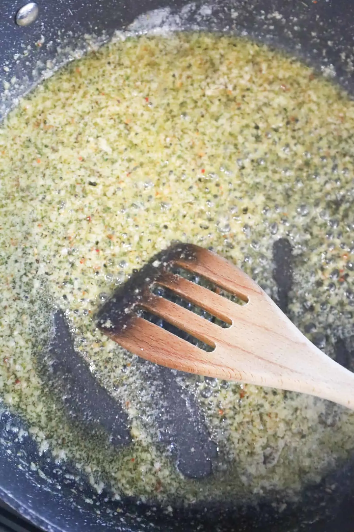 garlic puree and Italian seasoning and melted butter being stirred in a skillet