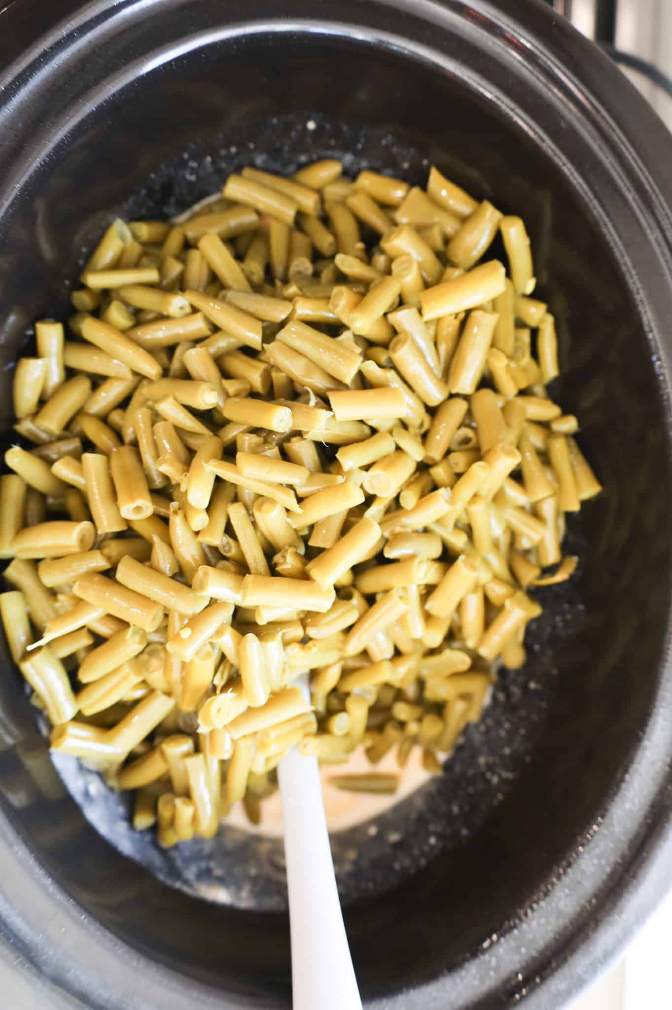 canned cut green beans on top of soup mixture in a slow cooker