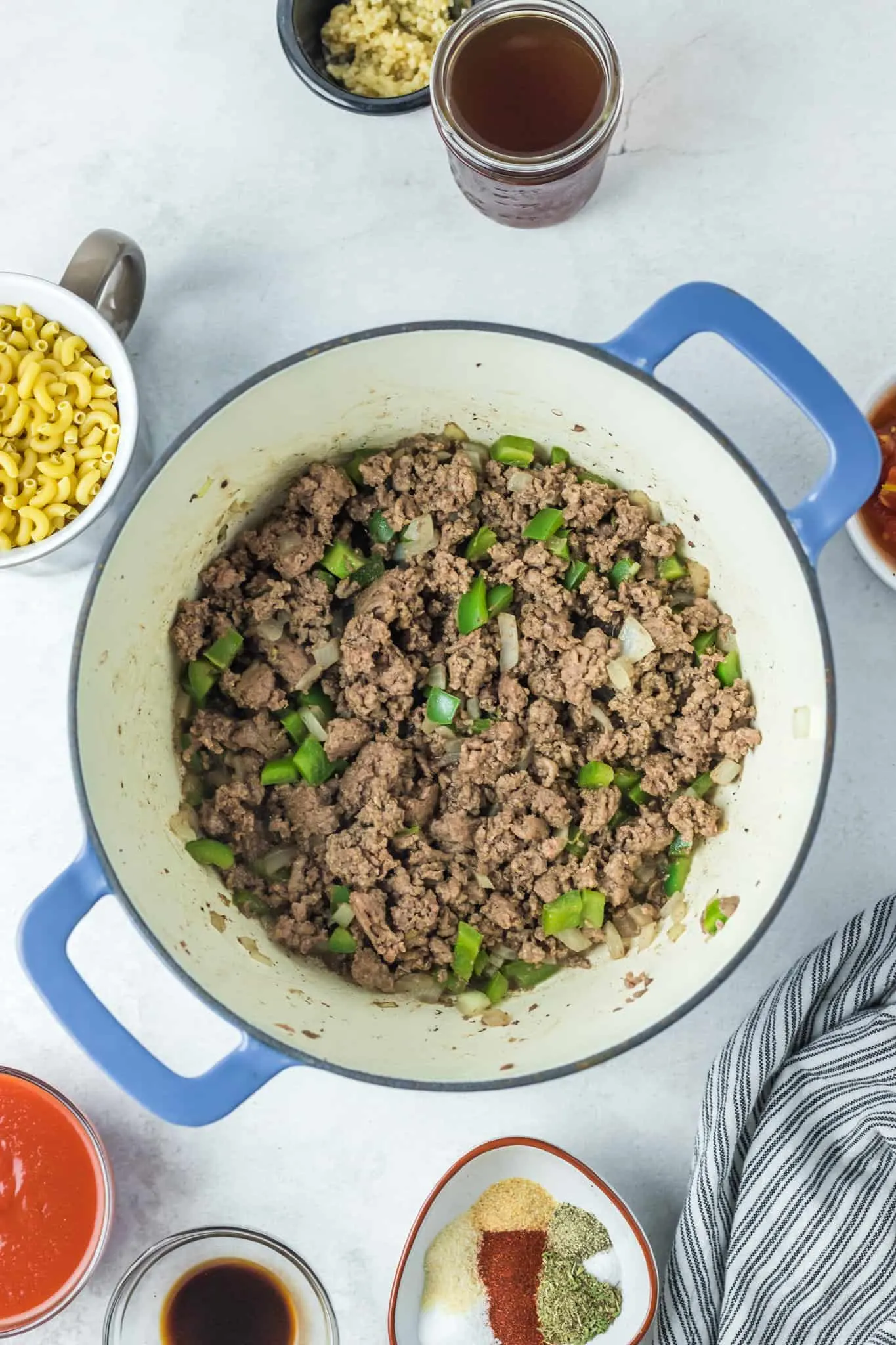 browned ground beef and diced green peppers in a pot
