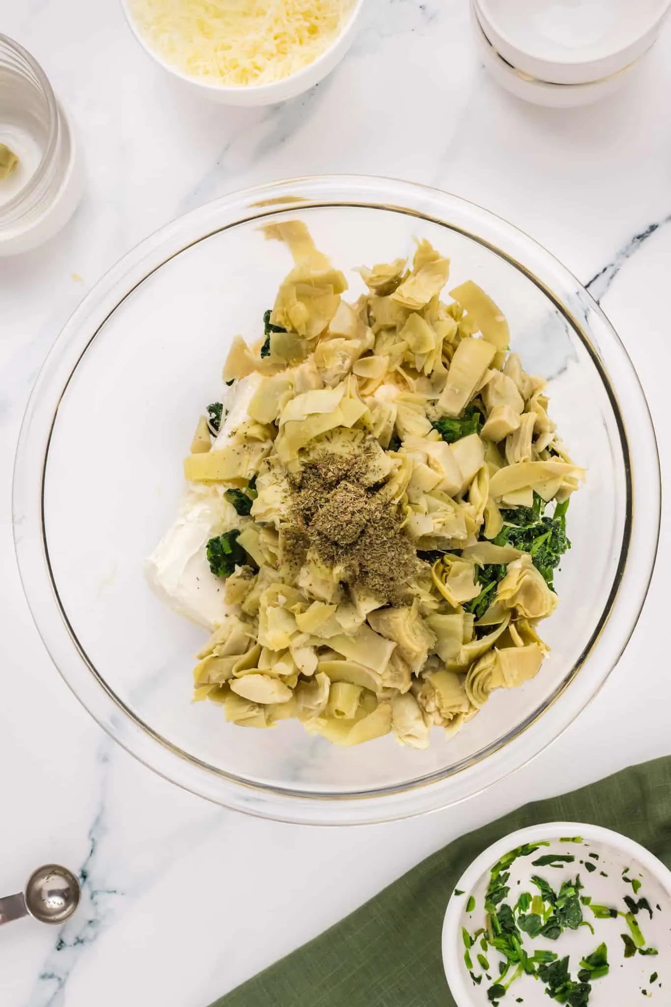 Italian seasoning, chopped artichoke hearts, chopped spinach and cream cheese in a mixing bowl