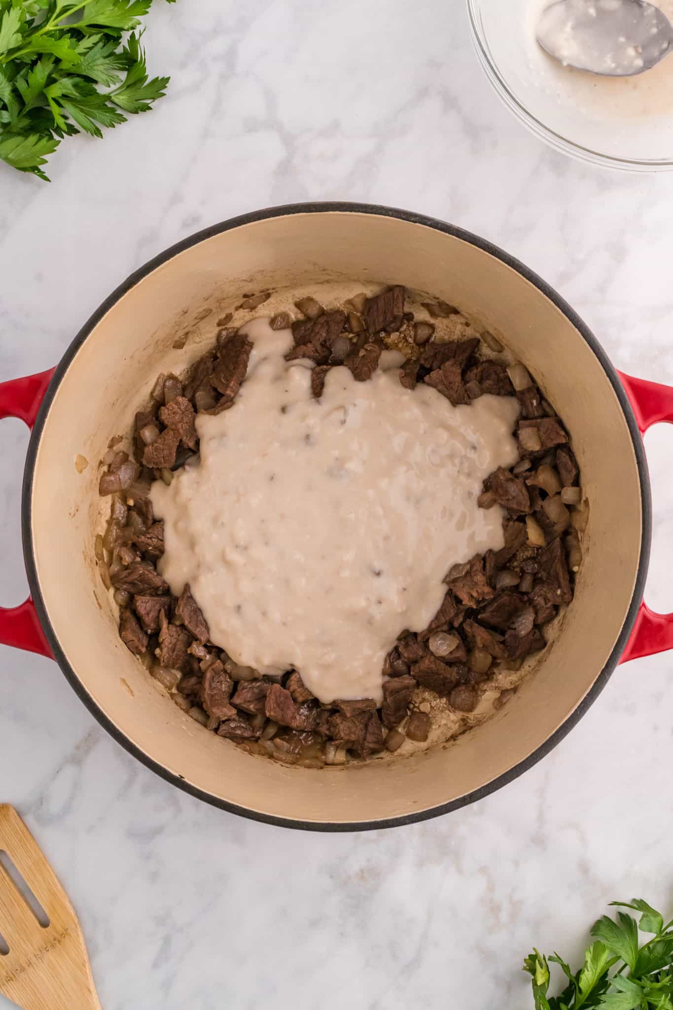 cream of mushroom soup mixture poured over steak pieces in a dutch oven